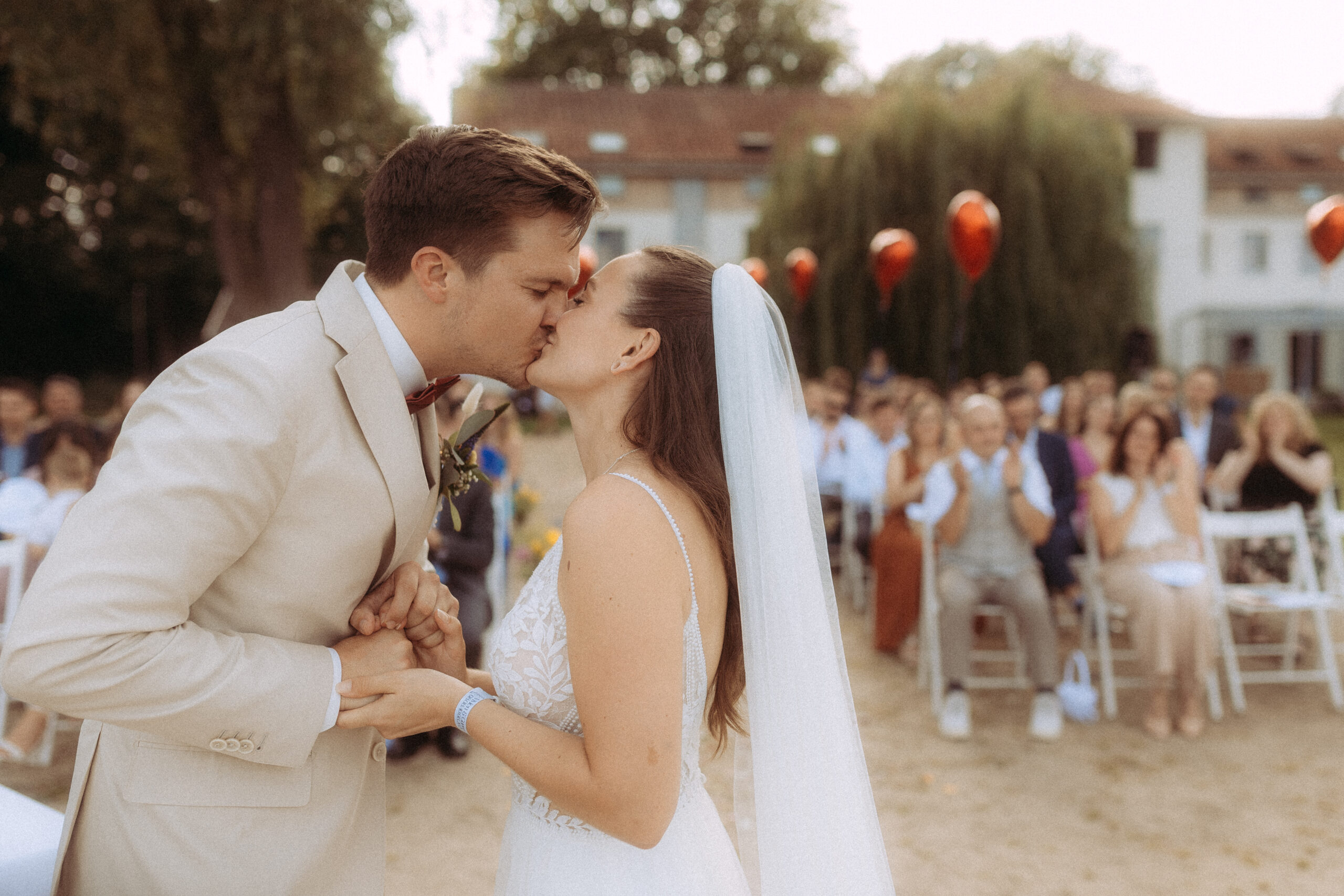 Brautpaar küsst sich bei Hochzeit am Haus Heinz am See vor Gästen