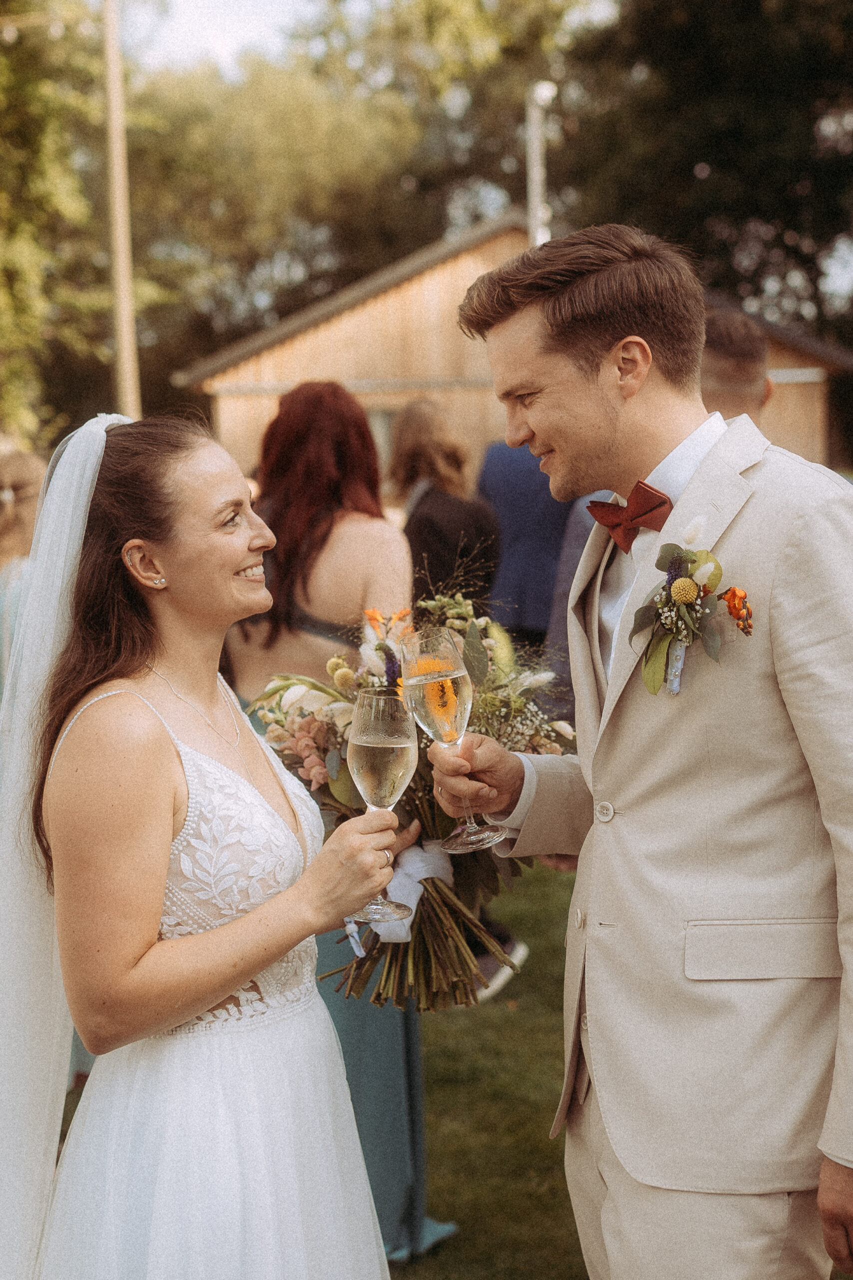 Brautpaar stößt mit Sekt auf einer Hochzeit im Freien an