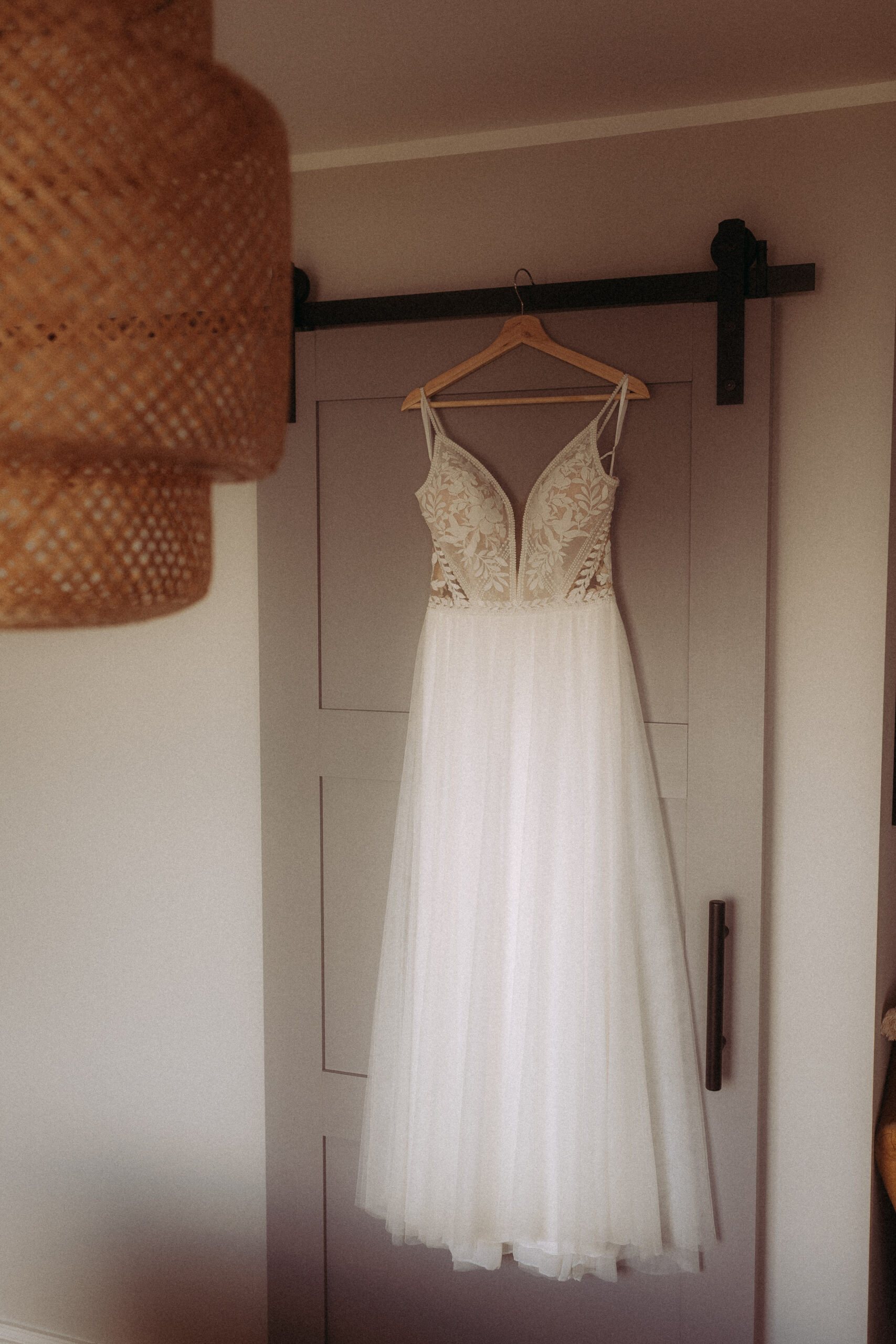 Elfenbeinfarbenes Brautkleid hängt an einer Schiebetür. Beweglicher Dreier Bezug möglich.