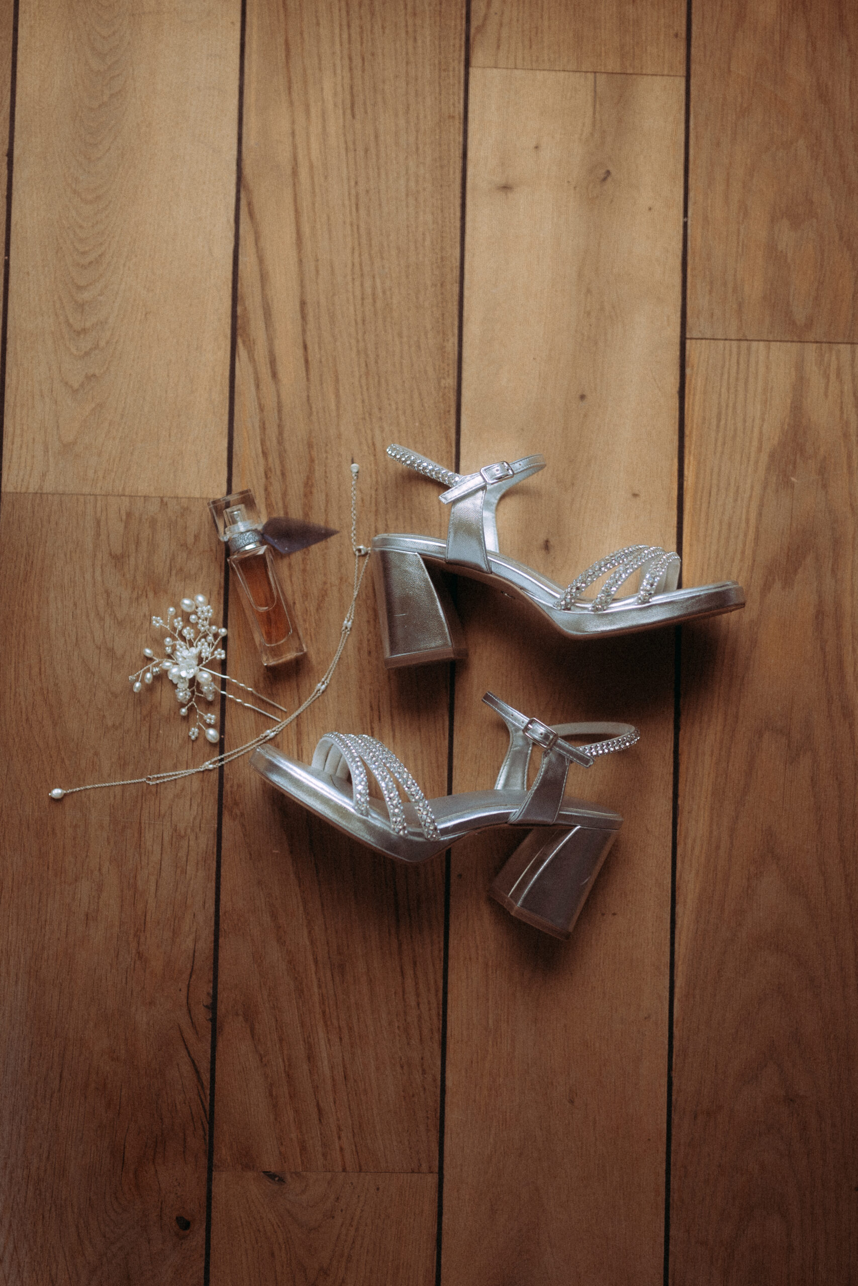 Brautschuhe, Parfum und Haarschmuck für die Hochzeit am Haus Heinz am See auf Holzboden
