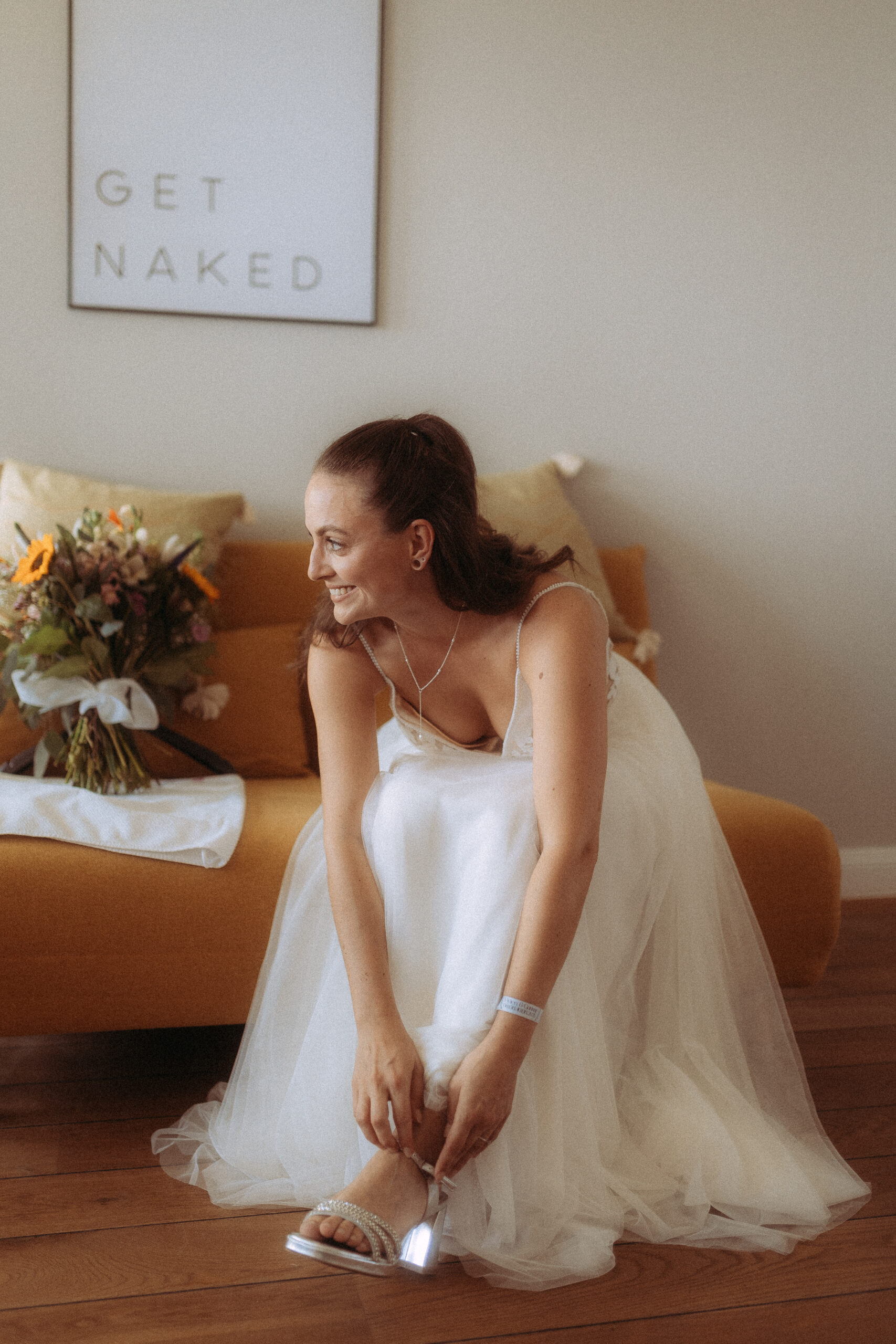 Braut zieht Schuhe an, Hochzeit am Haus Heinz am See. Schild mit 