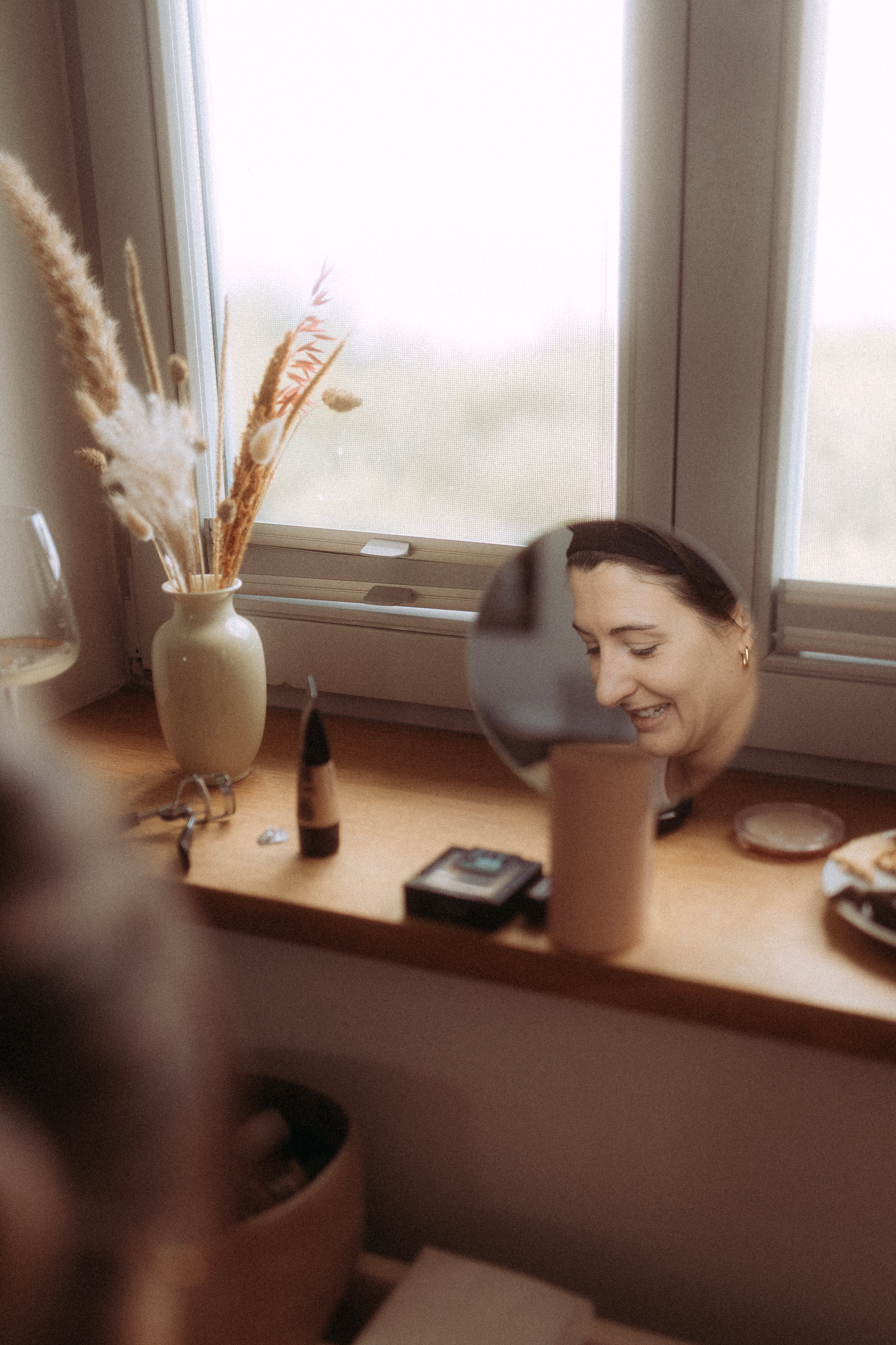 Frau lächelt im Spiegel, Babybauchshooting in Parchim, Fenster mit Dekoration