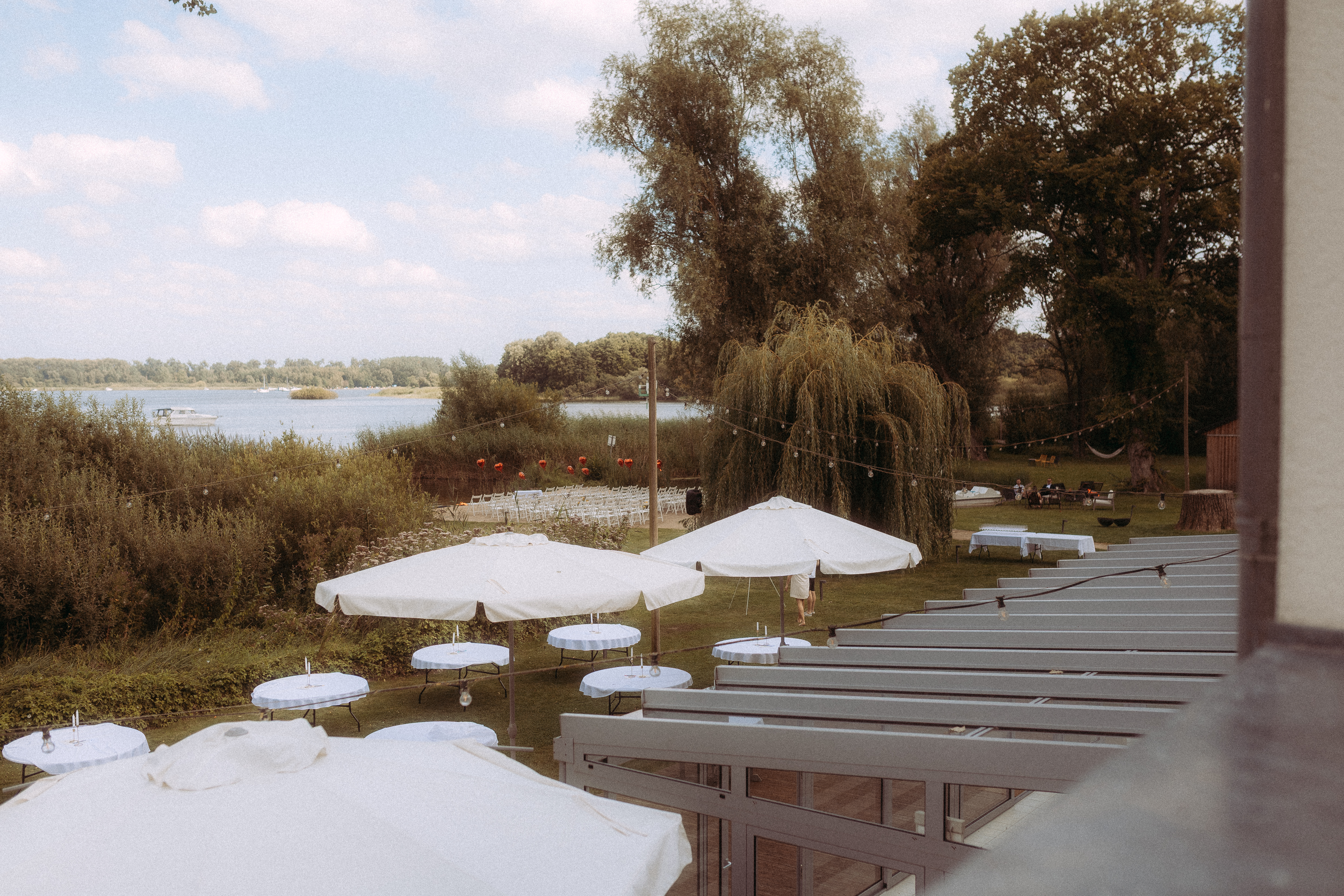 Hochzeitslocation am See mit weißen Sonnenschirmen und Tischen für ein Shooting beim Melchsee Frutt in der Schweiz.