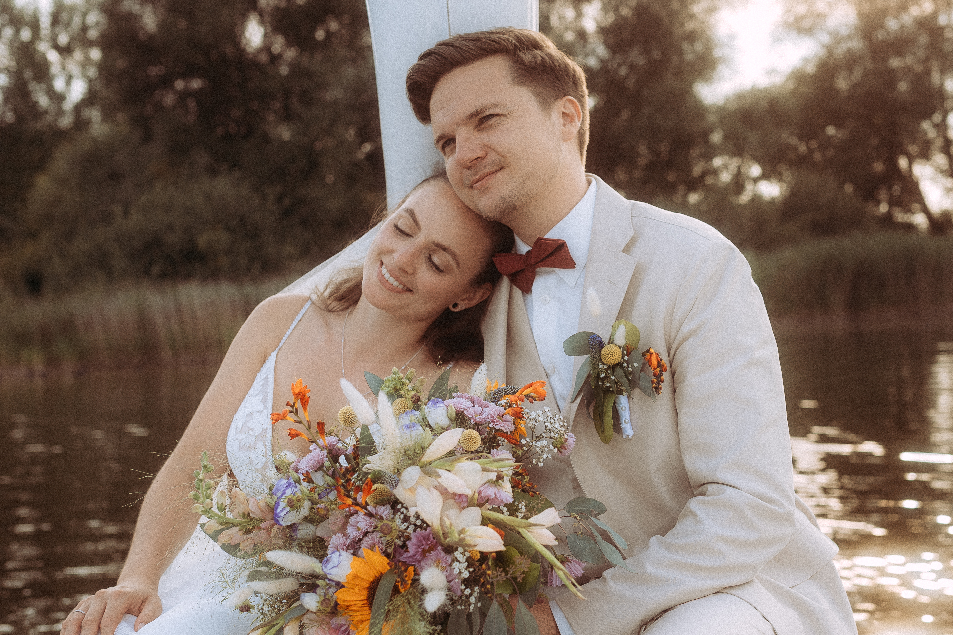 Brautpaar kuschelt am Haus Heinz am See mit Blumenstrauß, Hochzeit.