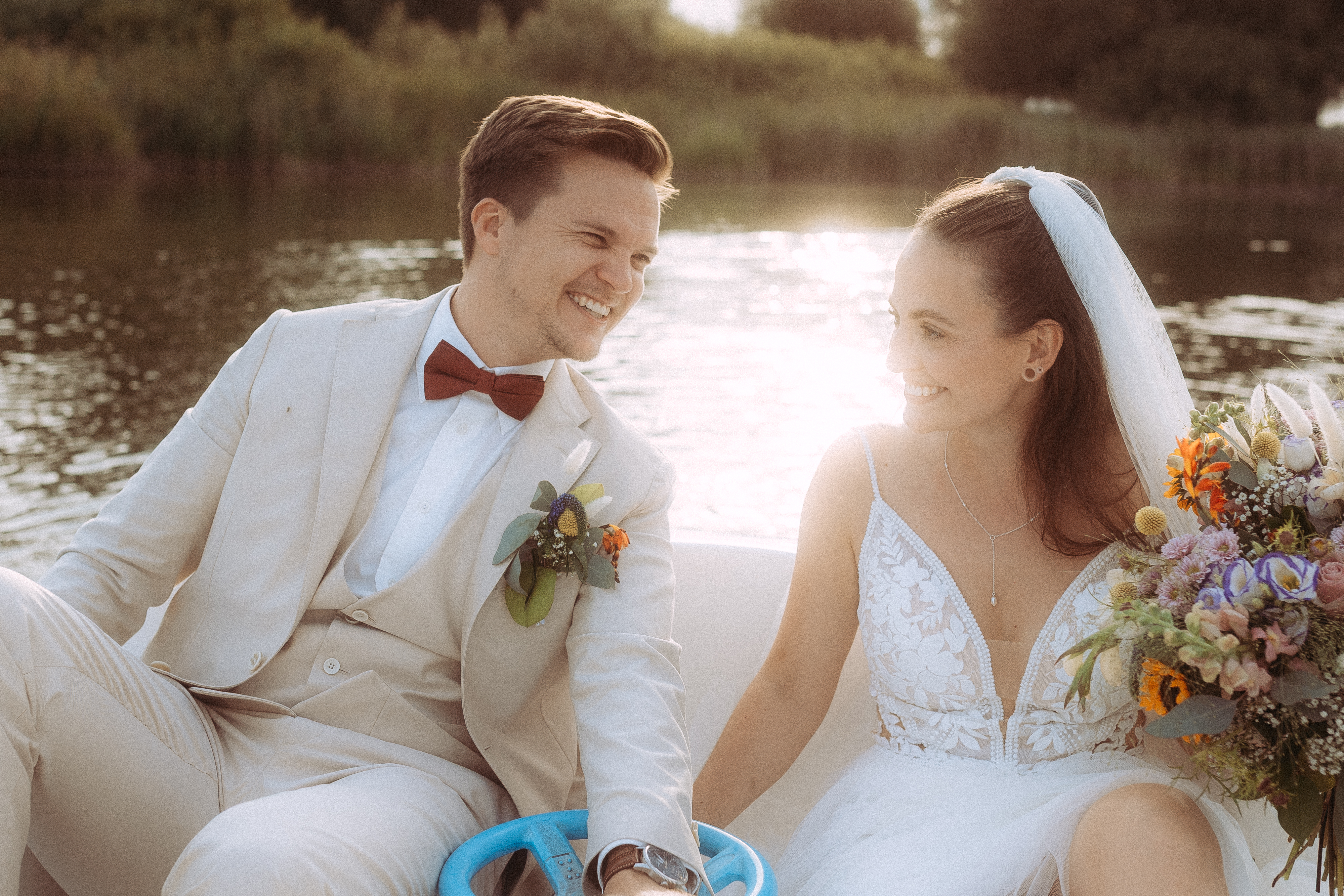 Brautpaar lacht verliebt auf einem Boot am Haus Heinz am See, Hochzeit