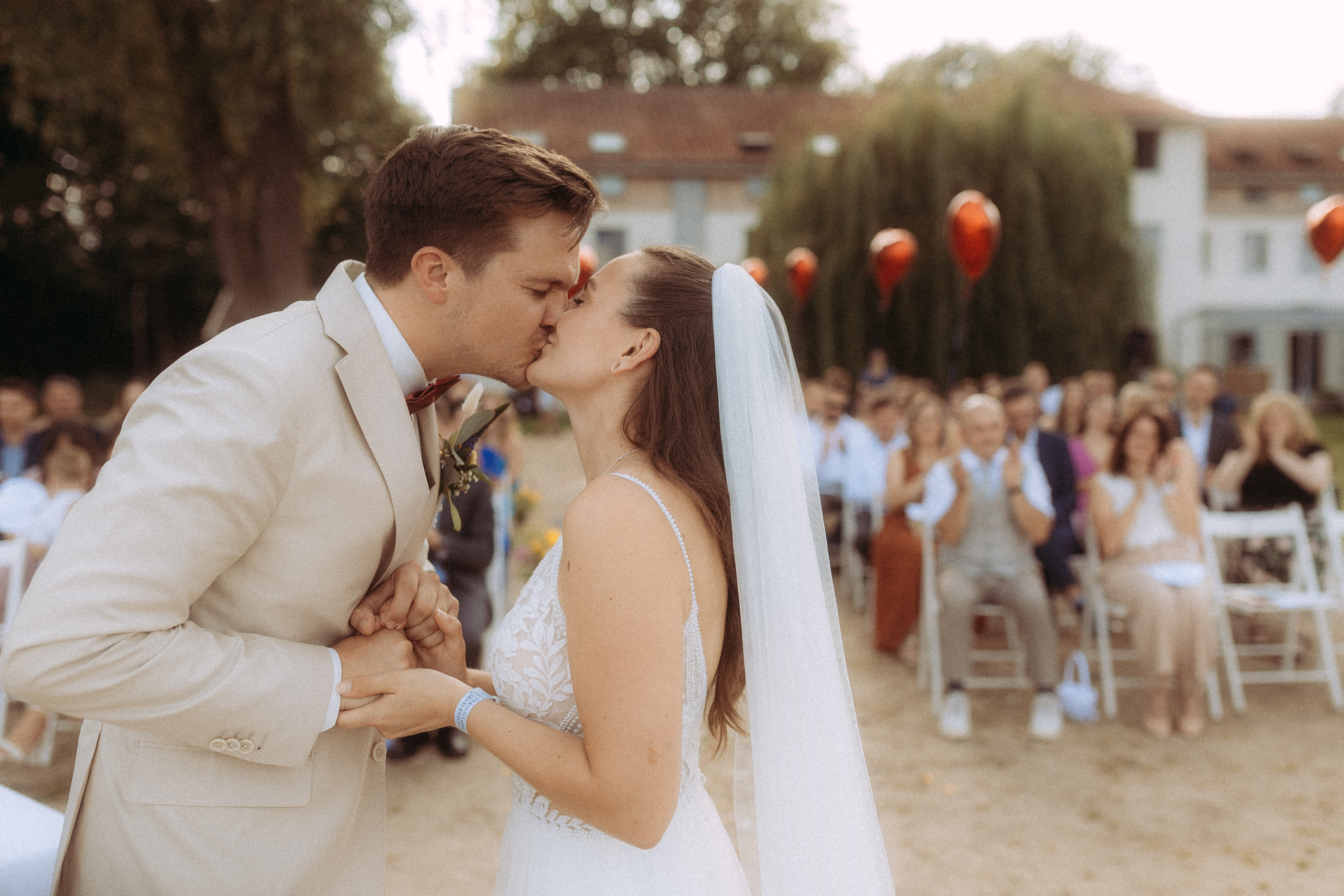 Brautpaar küsst sich bei Hochzeit am Haus Heinz am See vor Gästen
