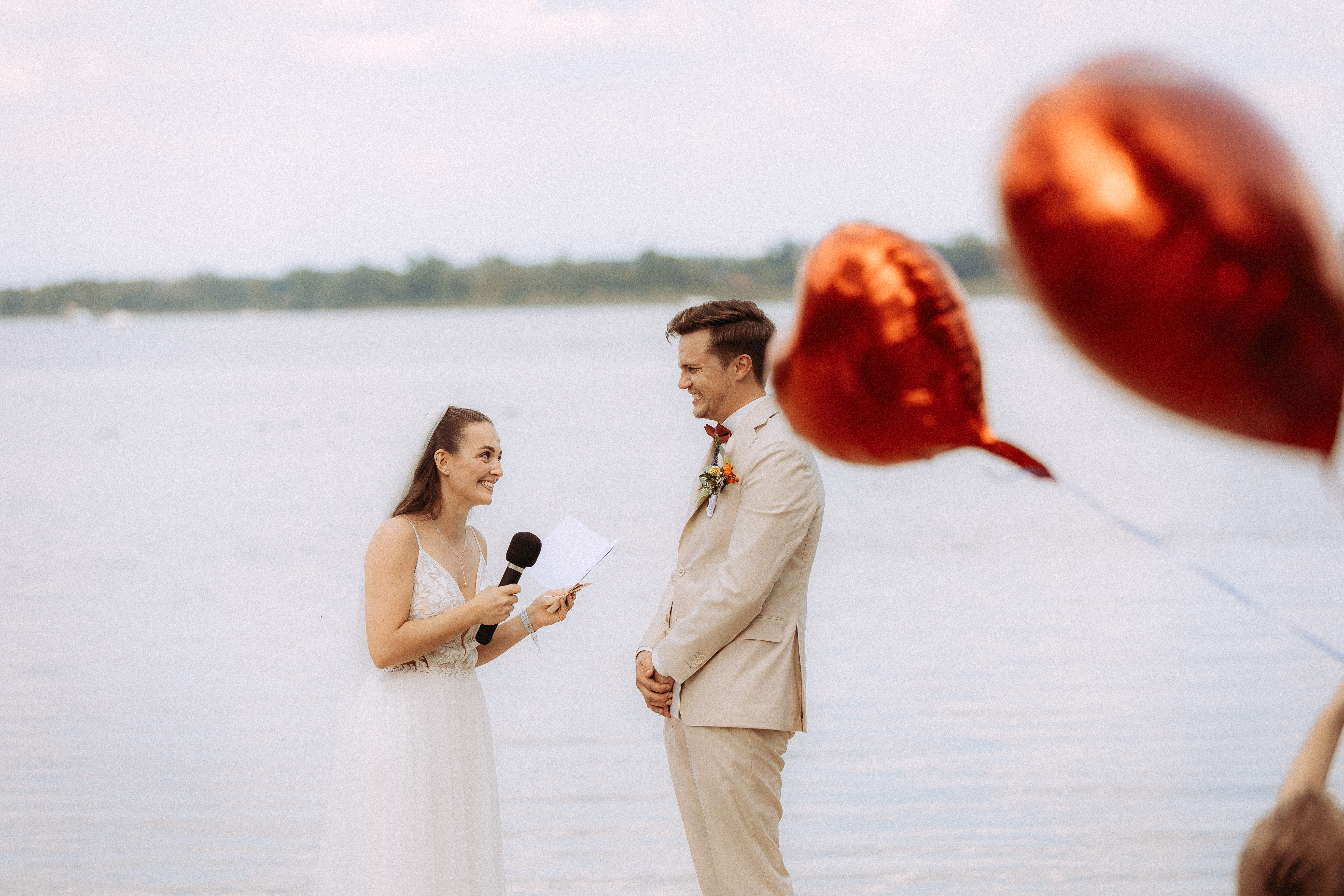 Brautpaar bei der Hochzeit am Haus Heinz am See, die Braut spricht ins Mikrofon.