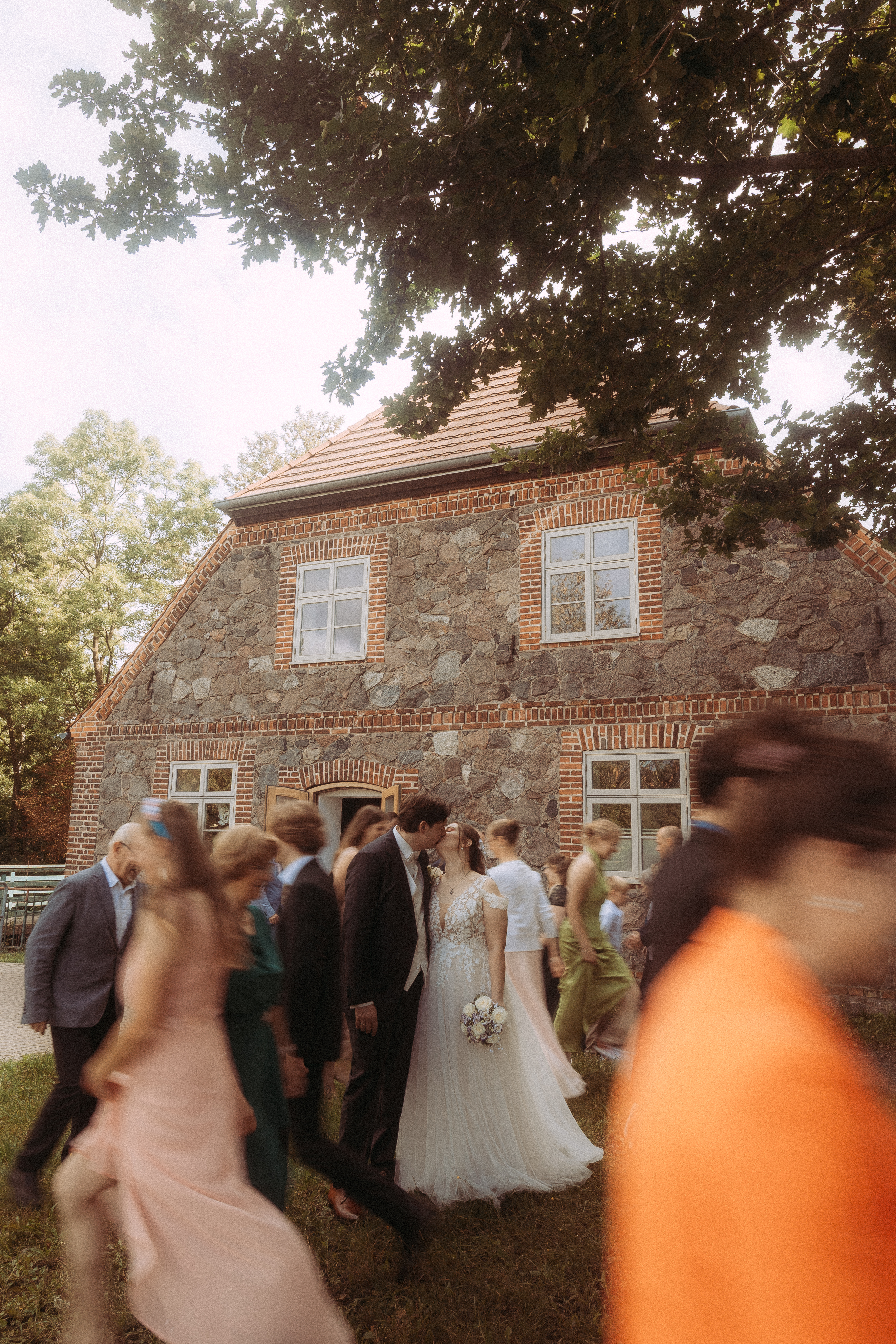 Brautpaar küsst sich vor dem Standesamt Friedland (MV), umgeben von Hochzeitsgästen.
