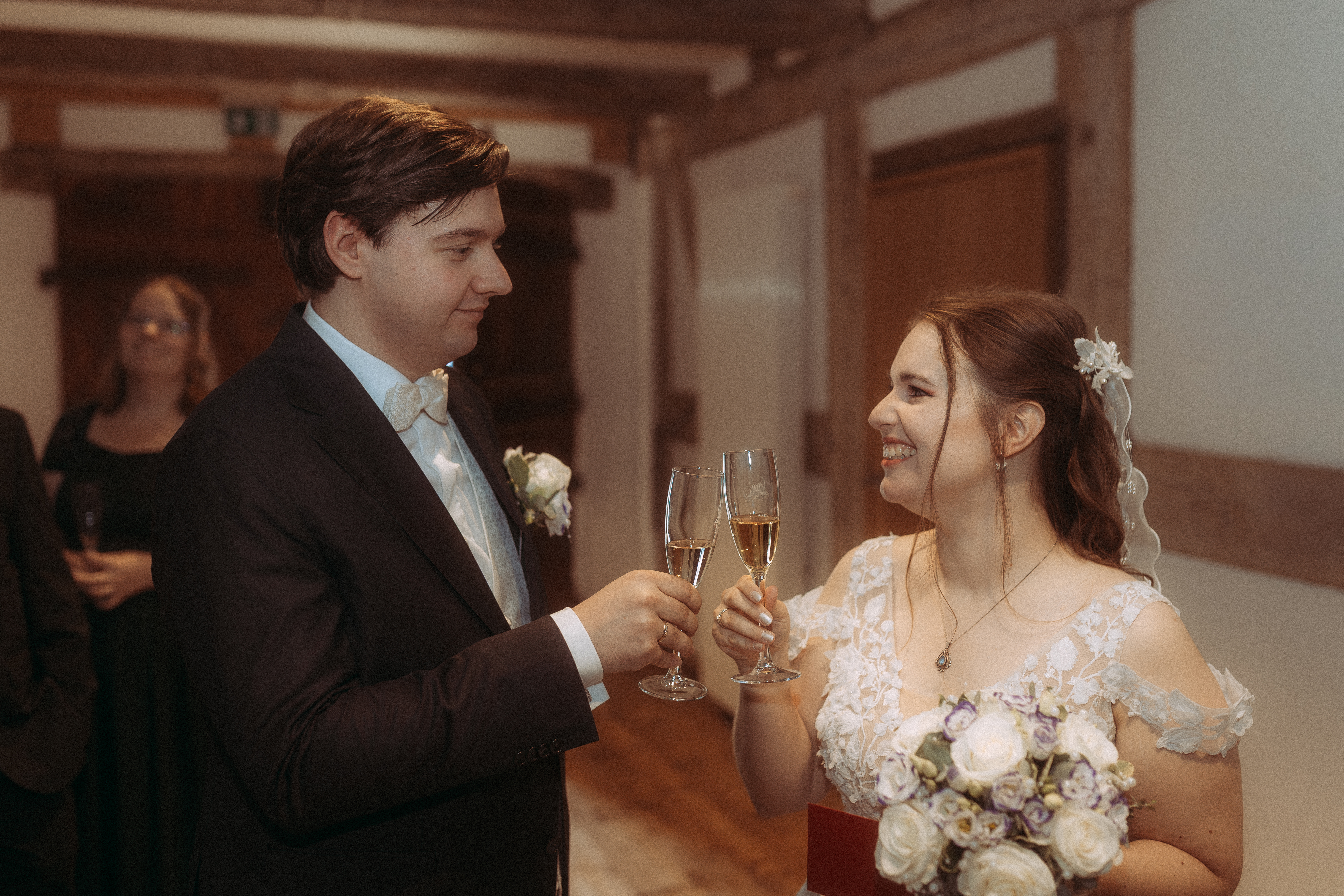 Brautpaar stößt mit Sektgläsern an, glücklich lächelnd. Hochzeit in festlicher Atmosphäre.