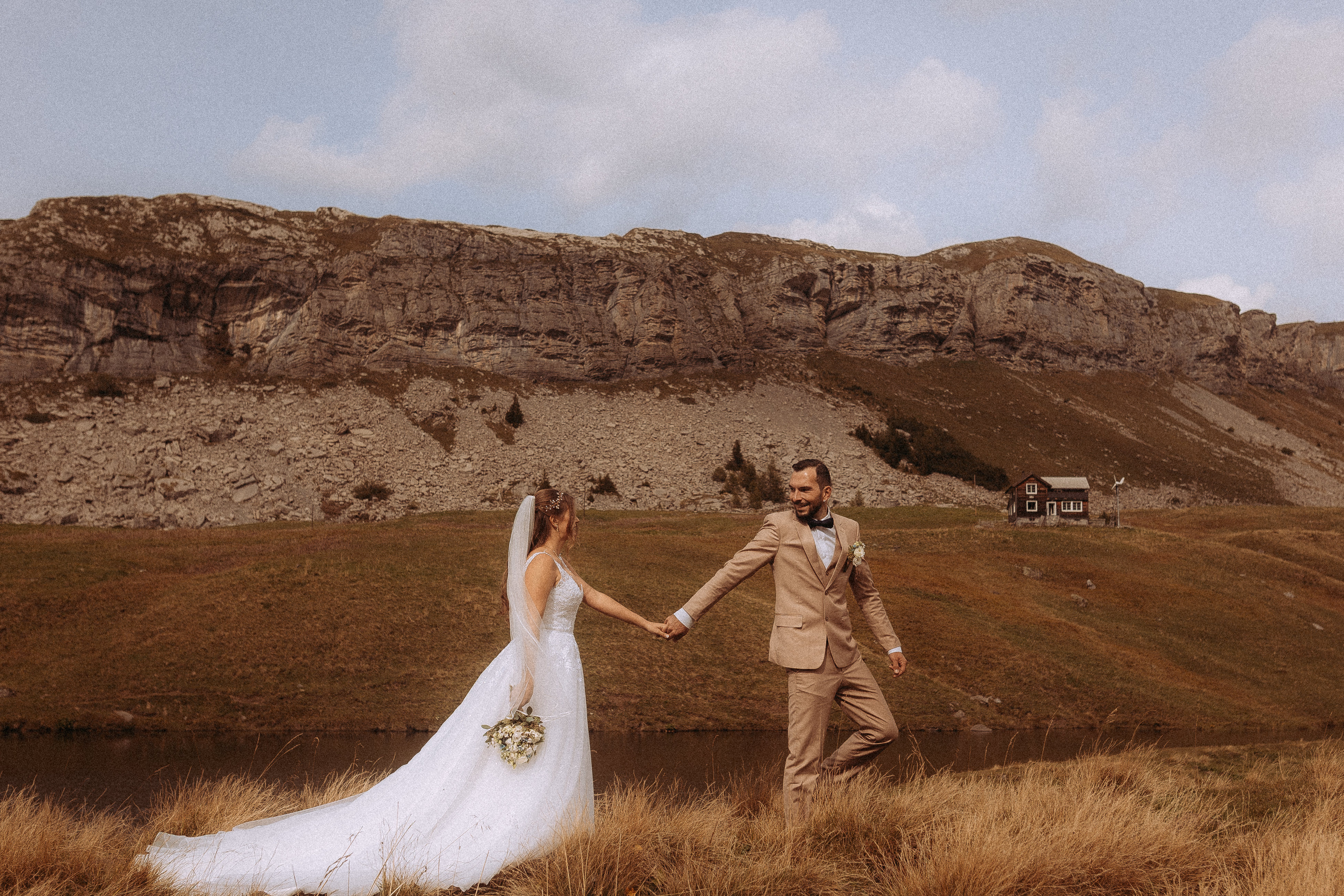 Brautpaar hält Händchen vor Bergkulisse beim Wedding Shooting Melchsee-Frutt Schweiz.