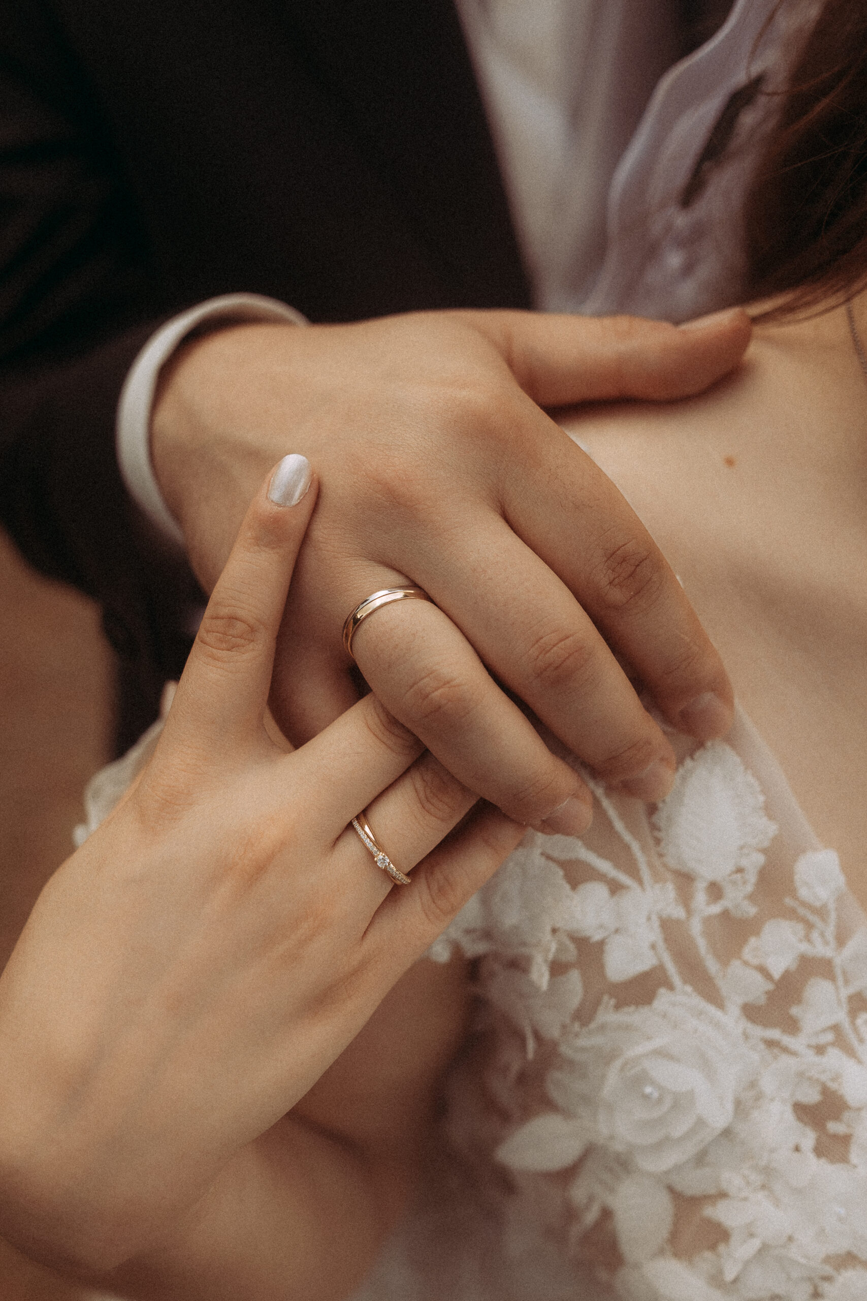 Hände mit Eheringen, Brautkleid mit floralen Details. Hochzeit