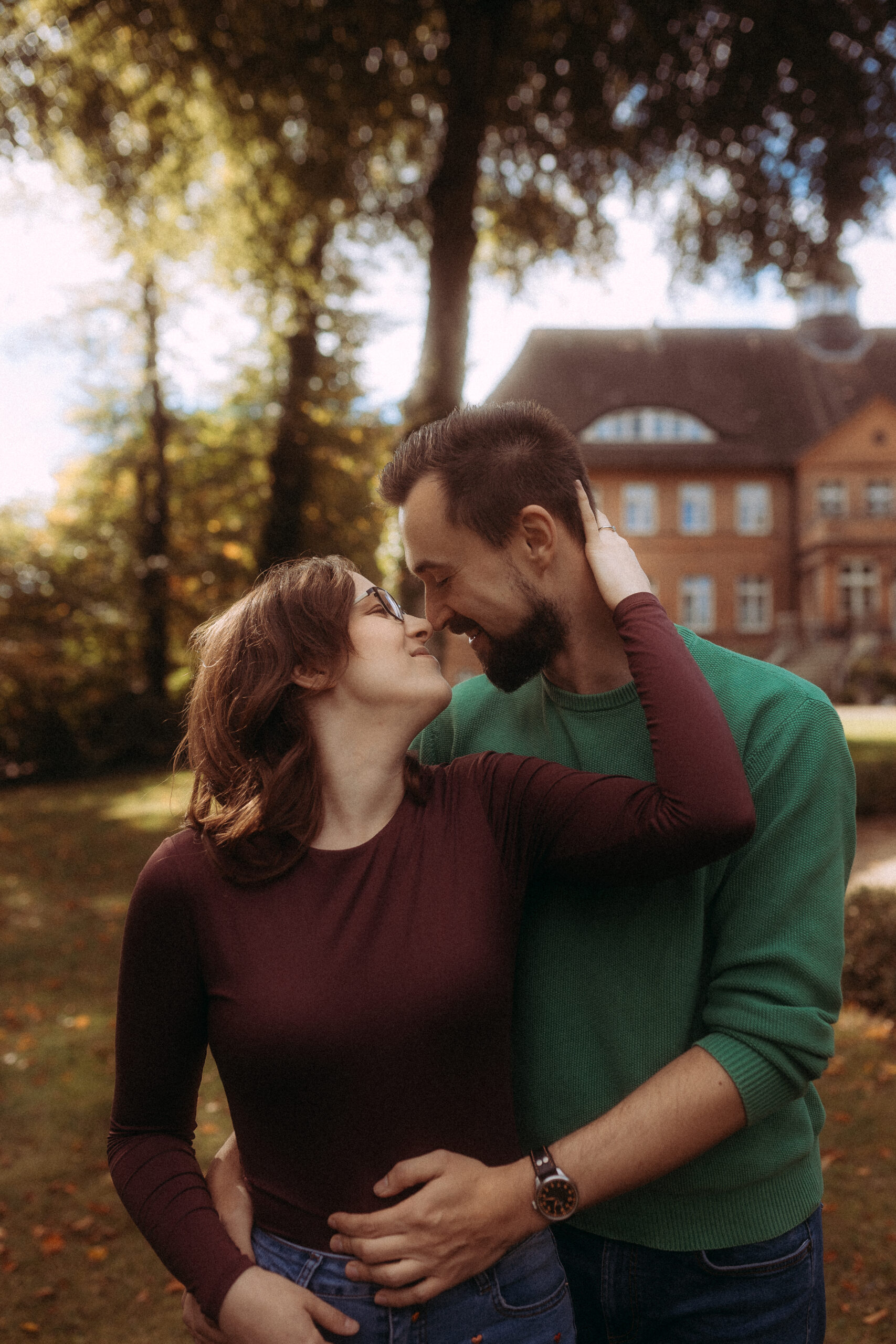 Verliebtes Paar umarmt sich zärtlich im Park vor einem Herrenhaus