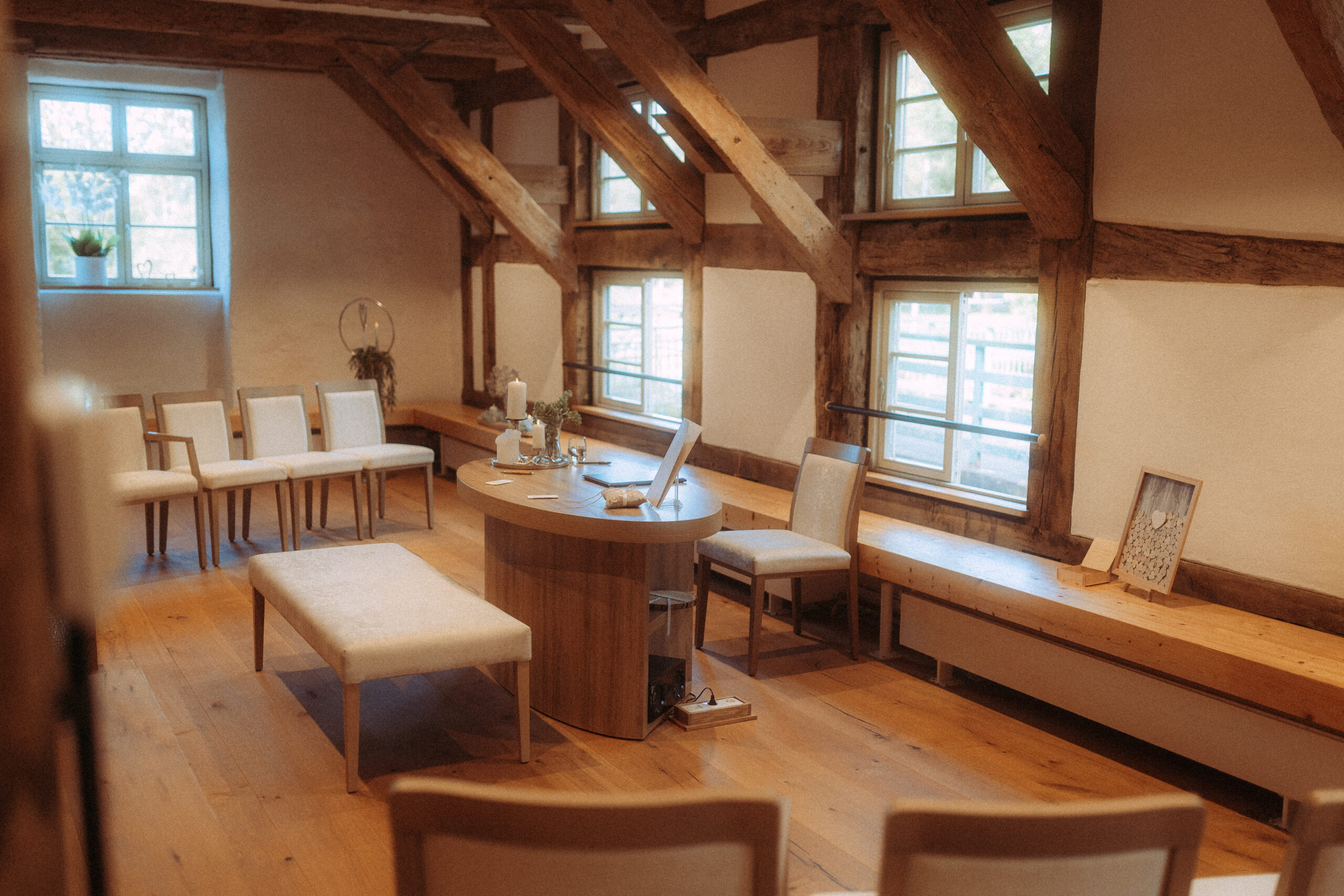 Hochzeitszimmer mit Holzbalken, Tisch und Stühlen. Rustikale Hochzeitslocation.