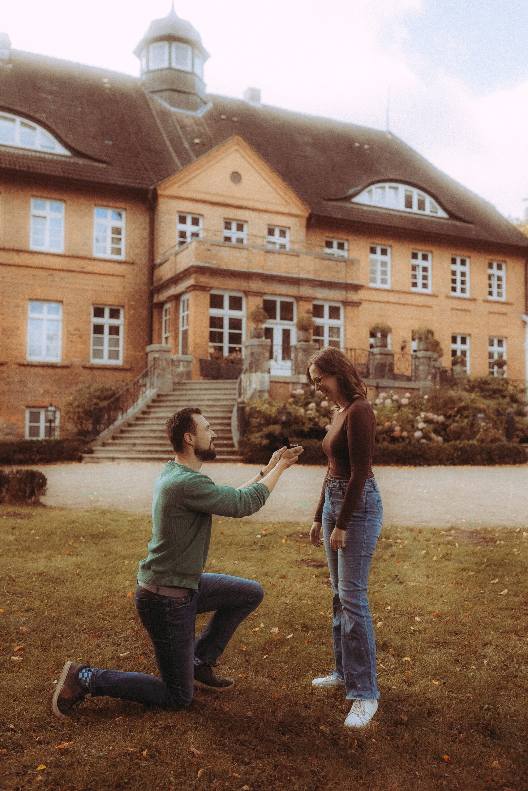 Mann macht Heiratsantrag vor einem Schloss. Romantischer Moment, Verlobung.