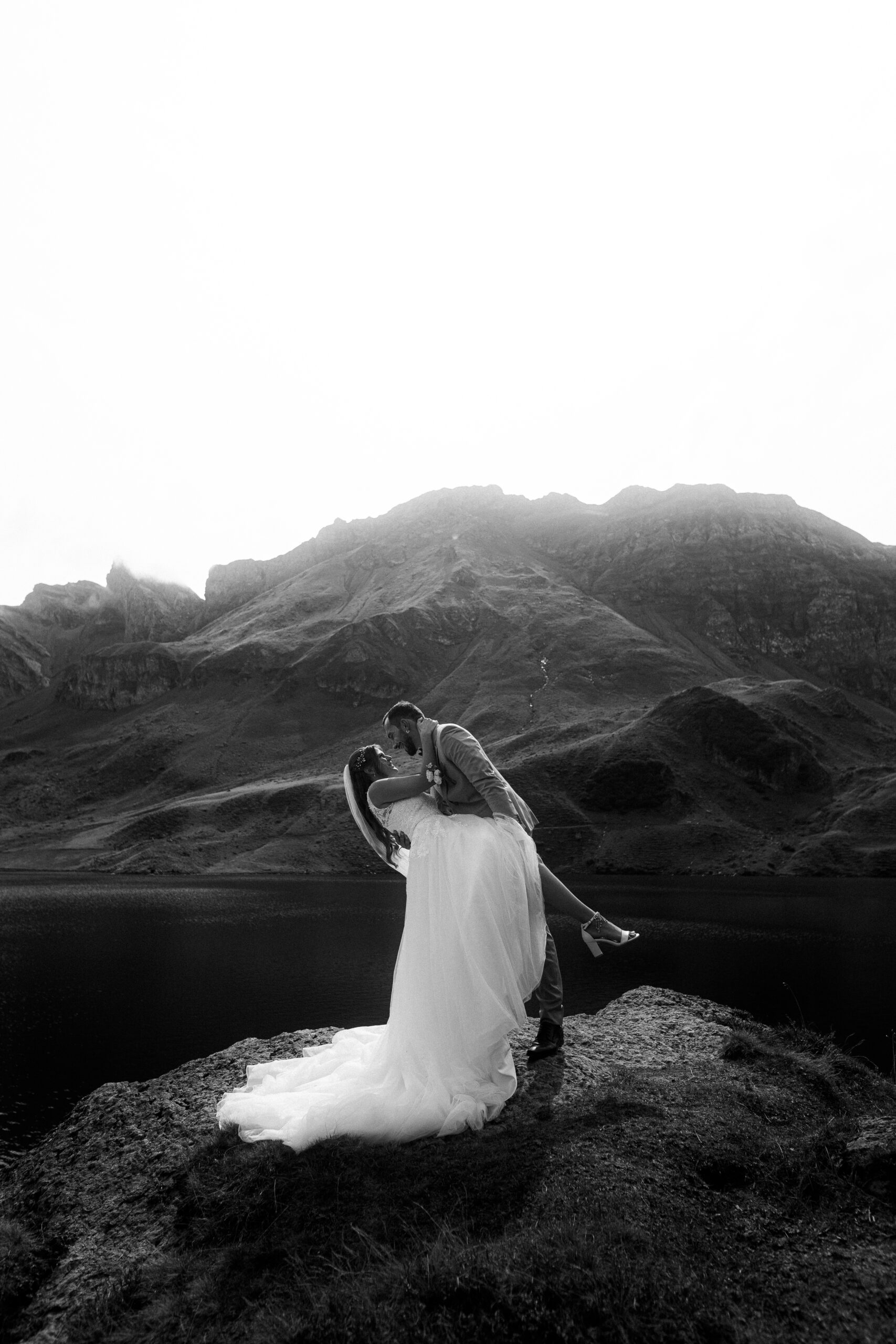 Hochzeitsshooting Melchsee Frutt: Brautpaar küsst sich vor Bergkulisse in der Schweiz.