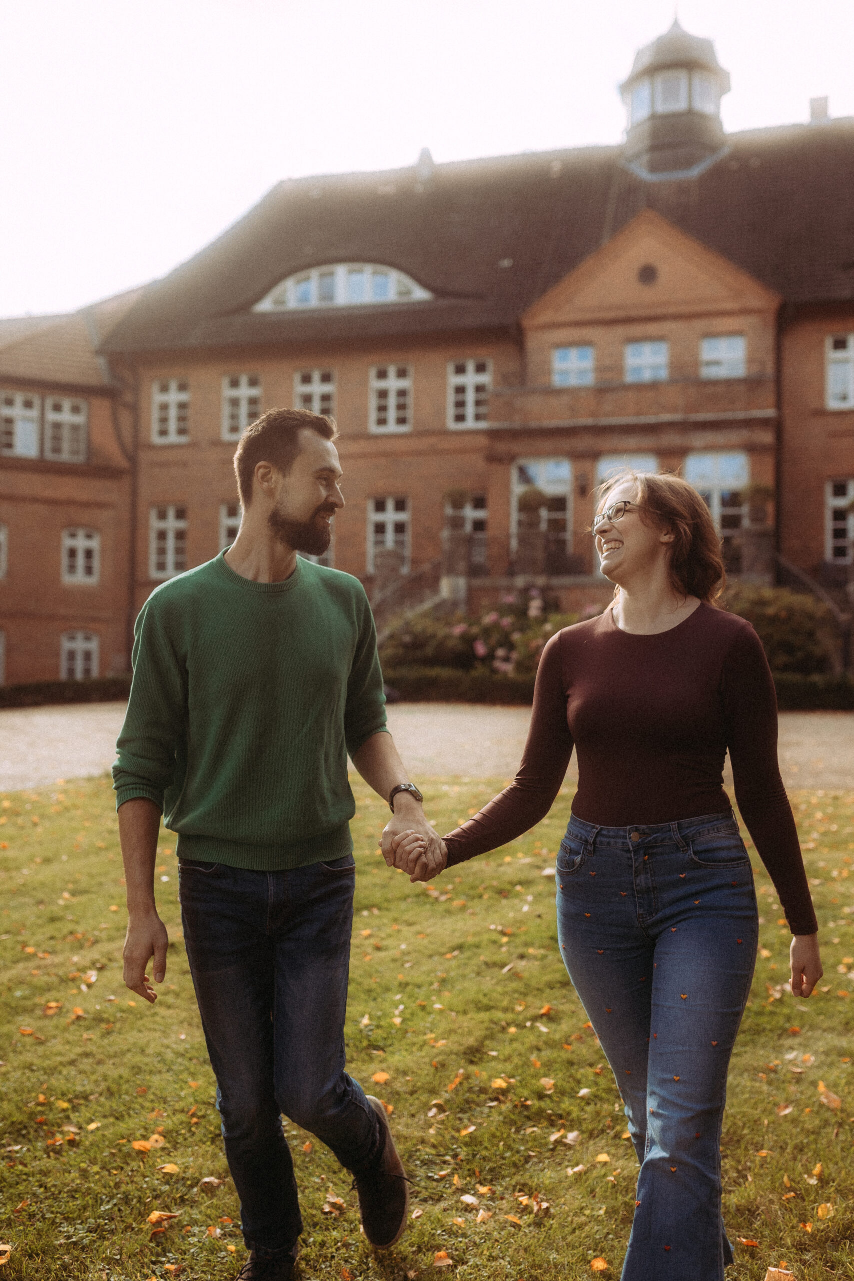 Paar Hand in Hand vor Haus Heinz am See. Hochzeit im Grünen.