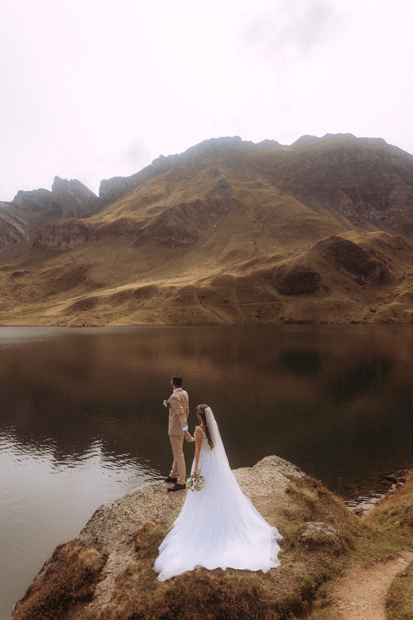 Hochzeitsshooting Melchsee Frutt: Brautpaar vor Bergsee in der Schweiz.