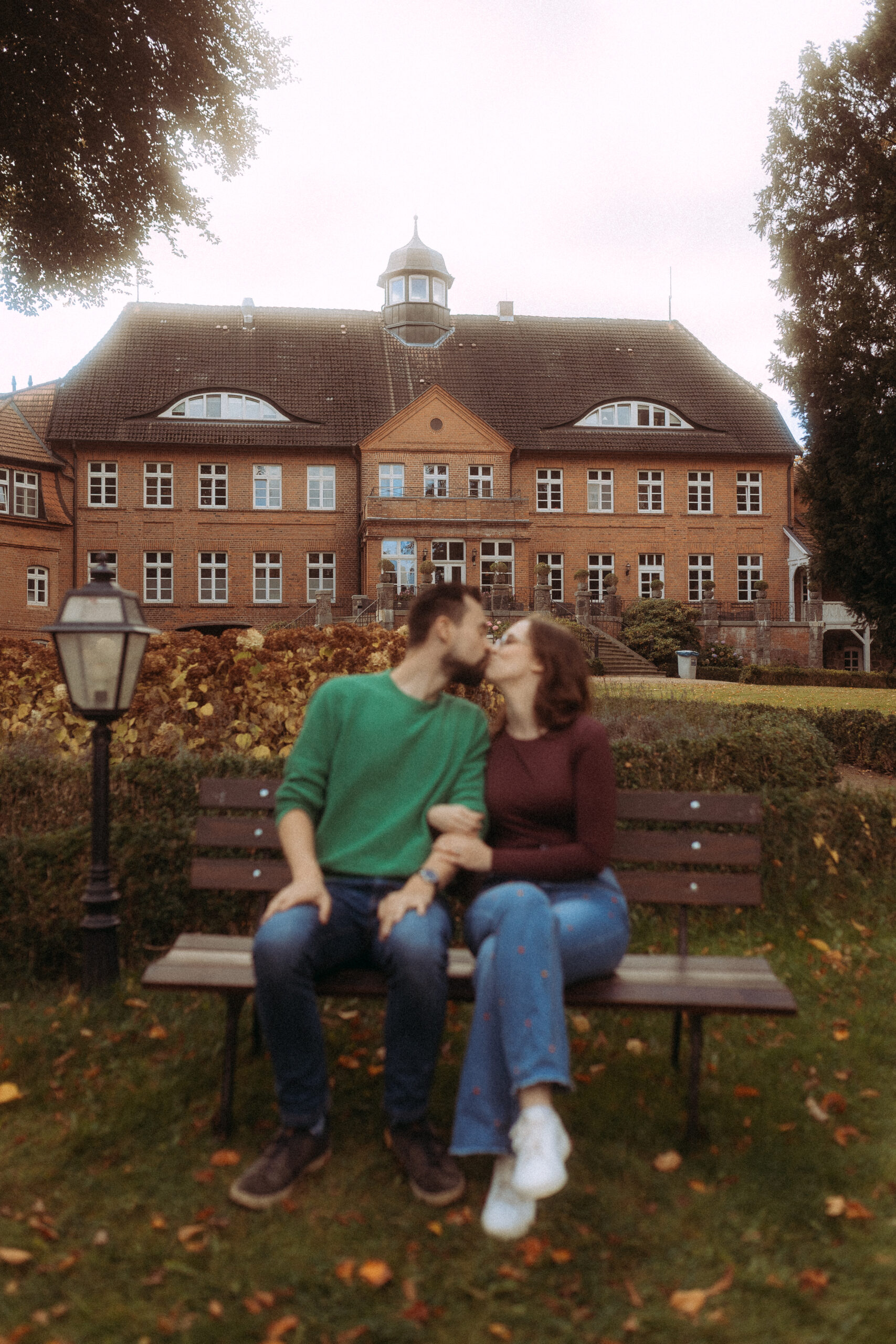 Küssendes Paar auf Bank vor Haus Heinz am See. Hochzeit.