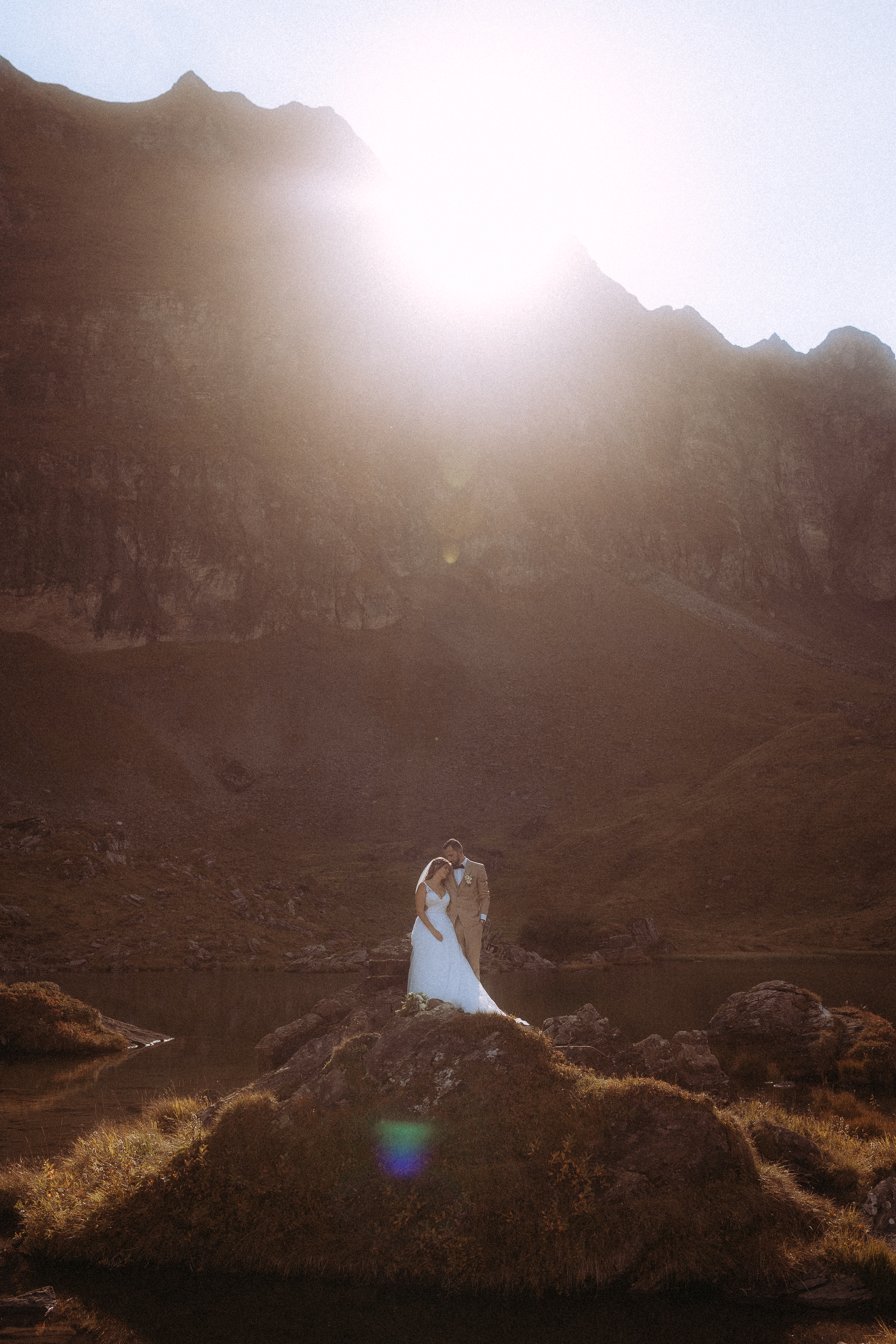 Hochzeitsshooting Melchsee-Frutt: Brautpaar vor Bergsee im Sonnenlicht.