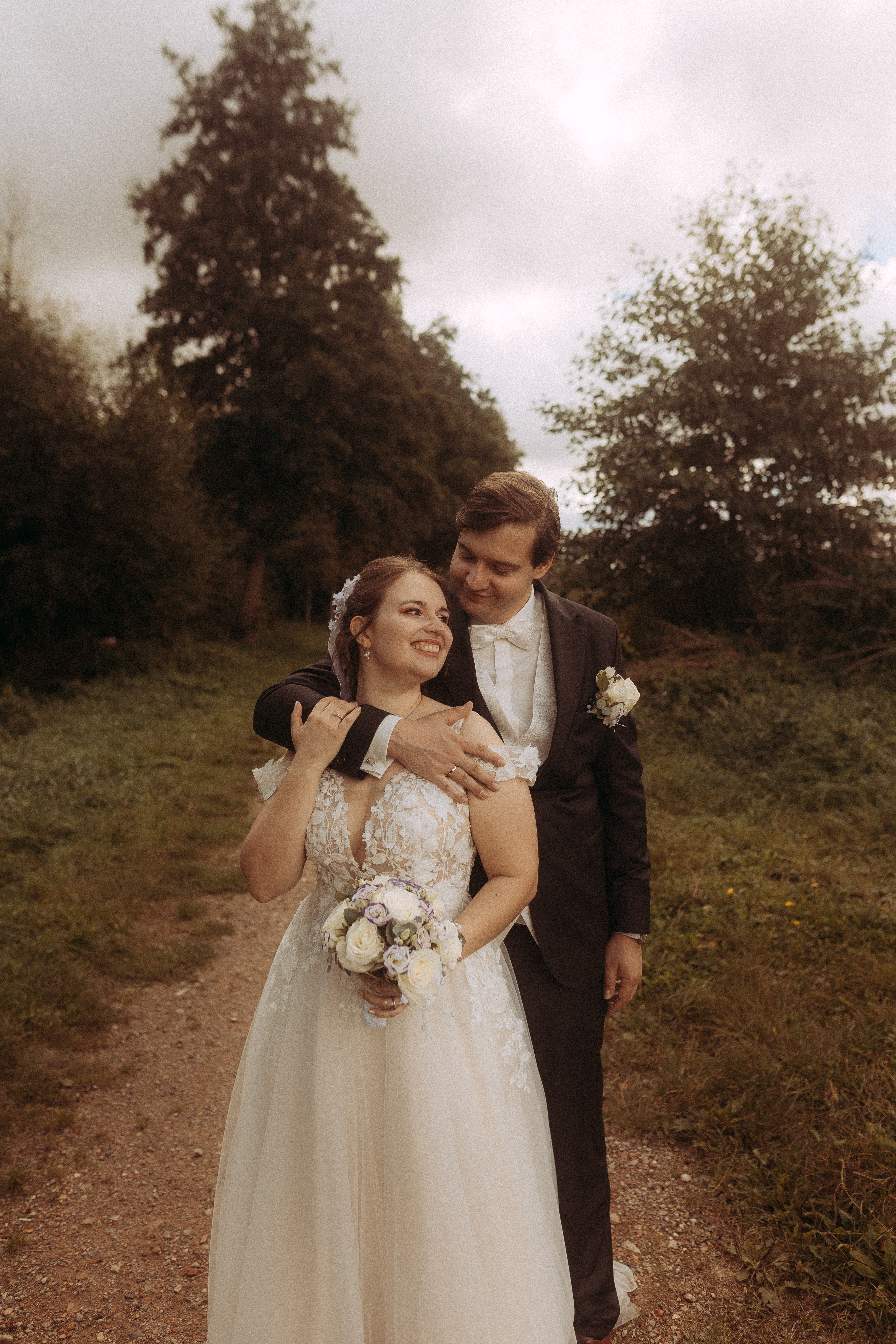 Brautpaar umarmt sich liebevoll vor malerischer Naturkulisse.