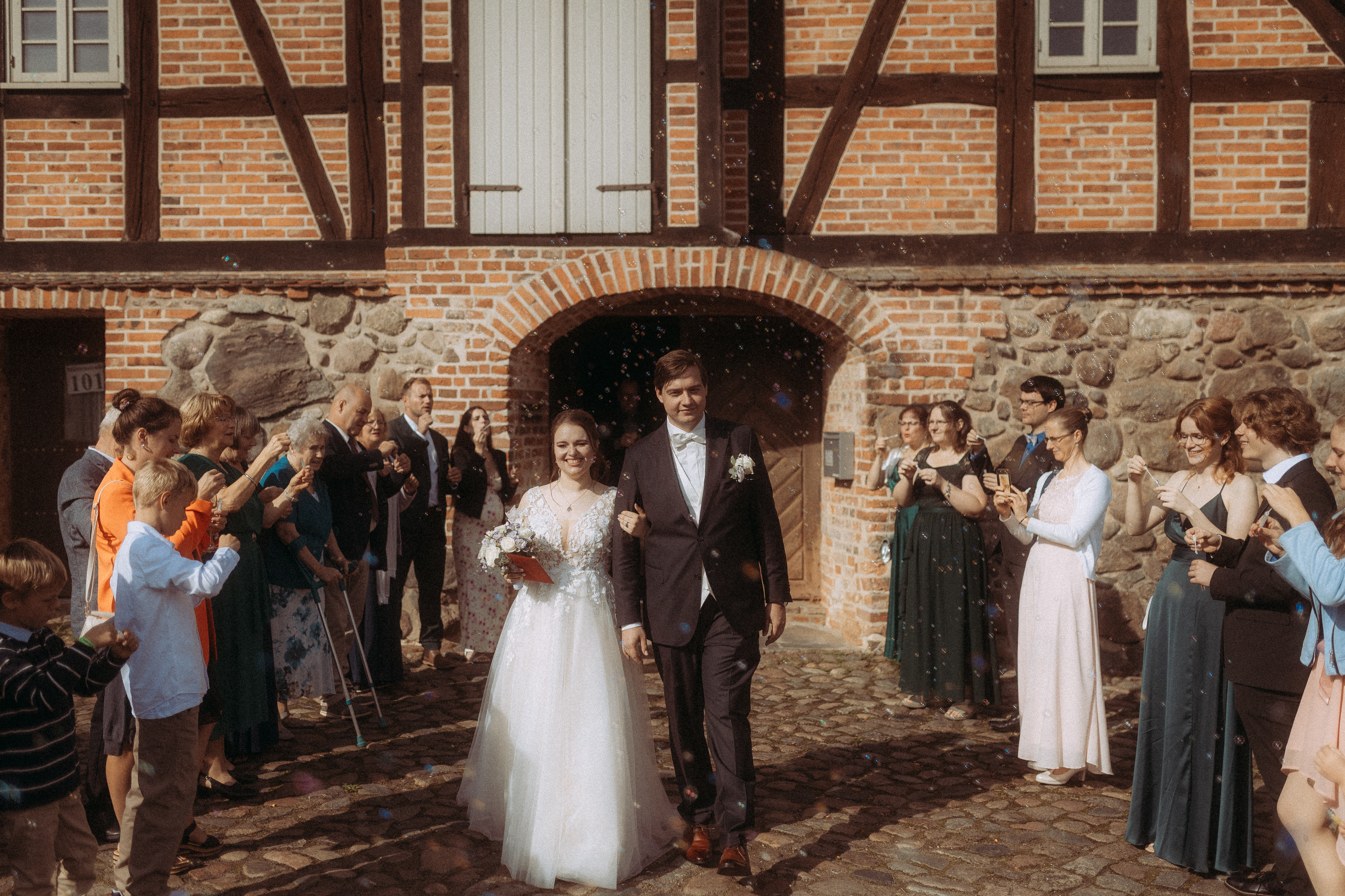 Brautpaar verlässt Standesamt Friedland (MV), umgeben von Gästen und Seifenblasen.