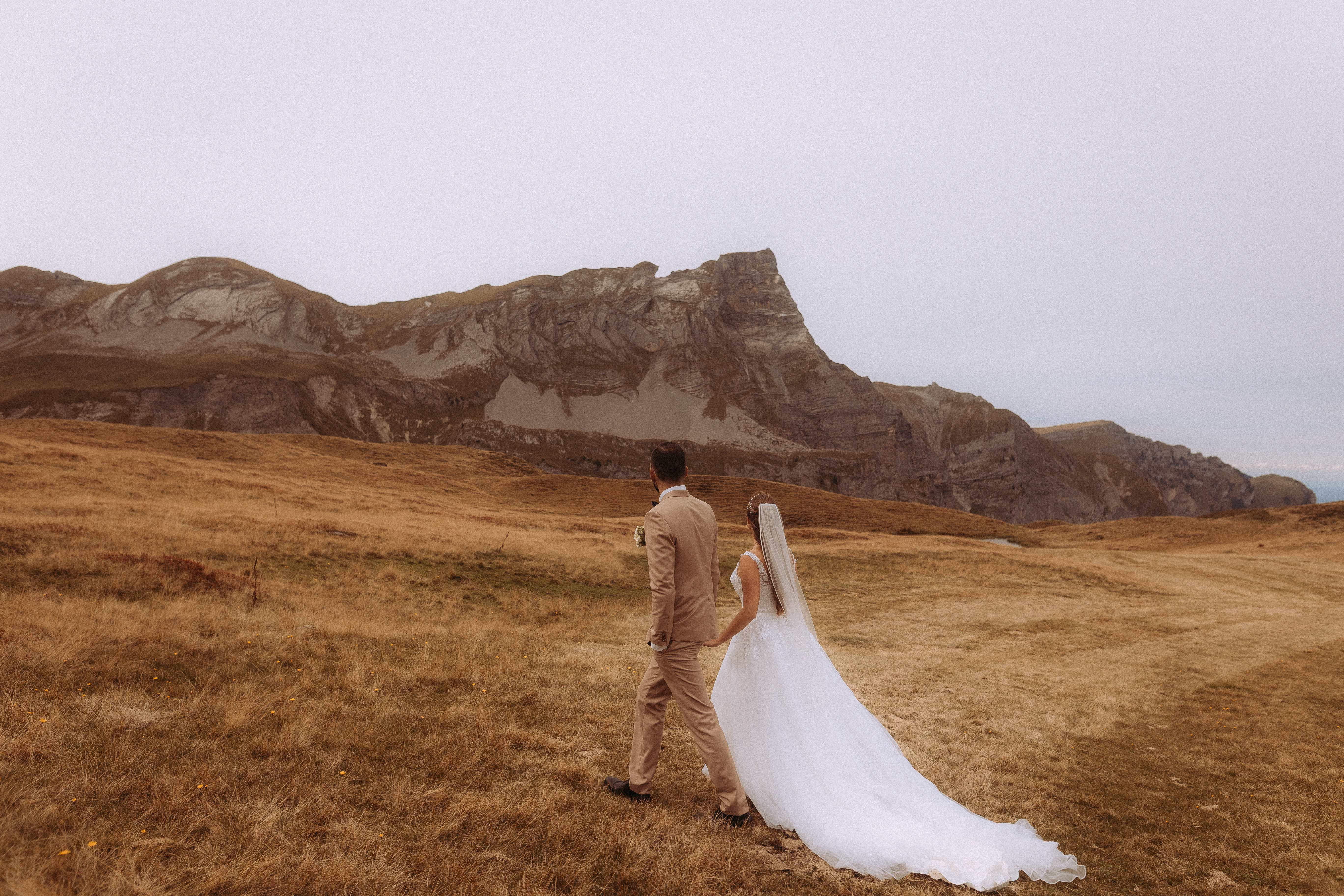 Hochzeitsshooting Melchsee Frutt: Brautpaar wandert vor Bergkulisse in der Schweiz.