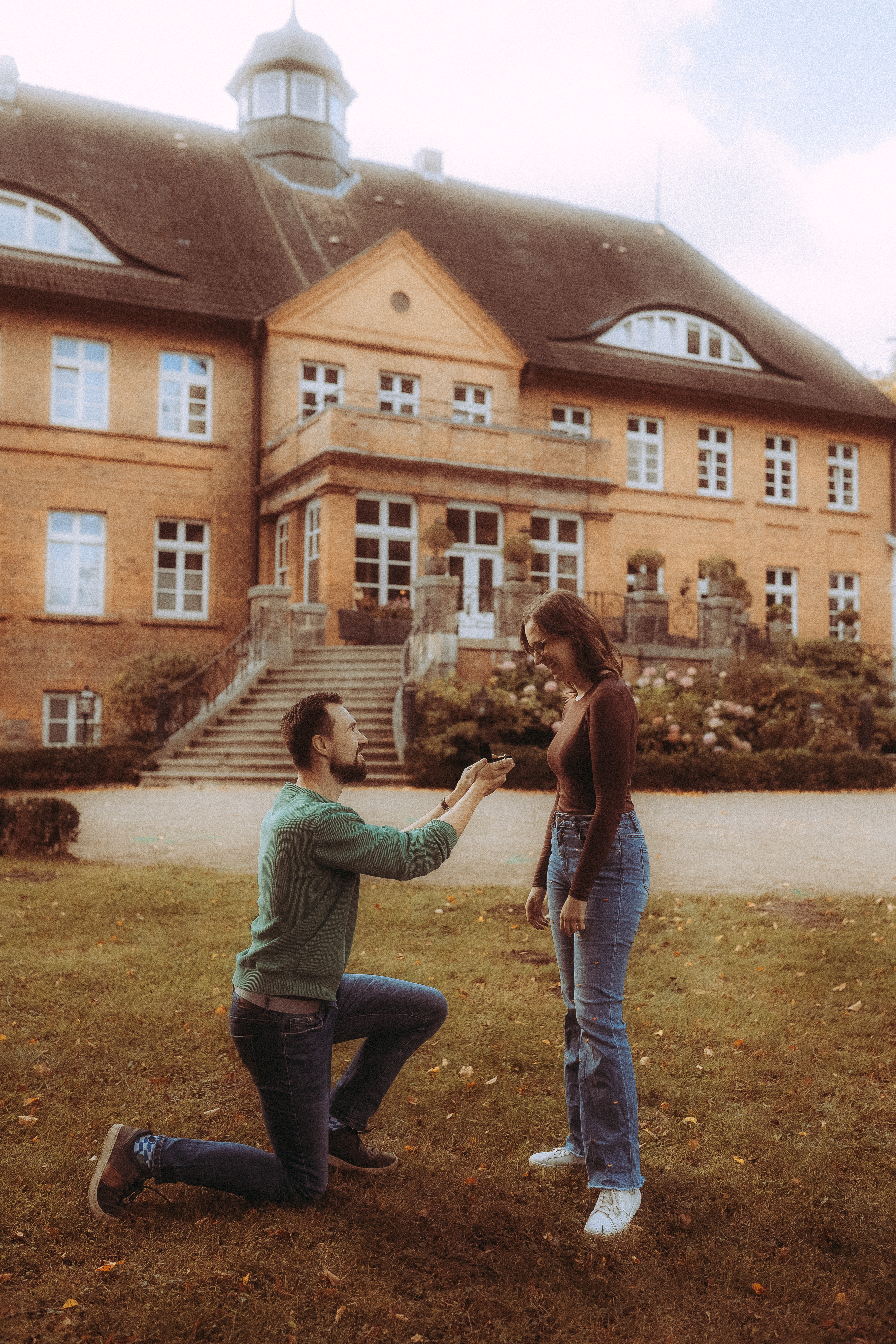Mann macht Heiratsantrag vor einem Schloss. Romantischer Moment, Verlobung.