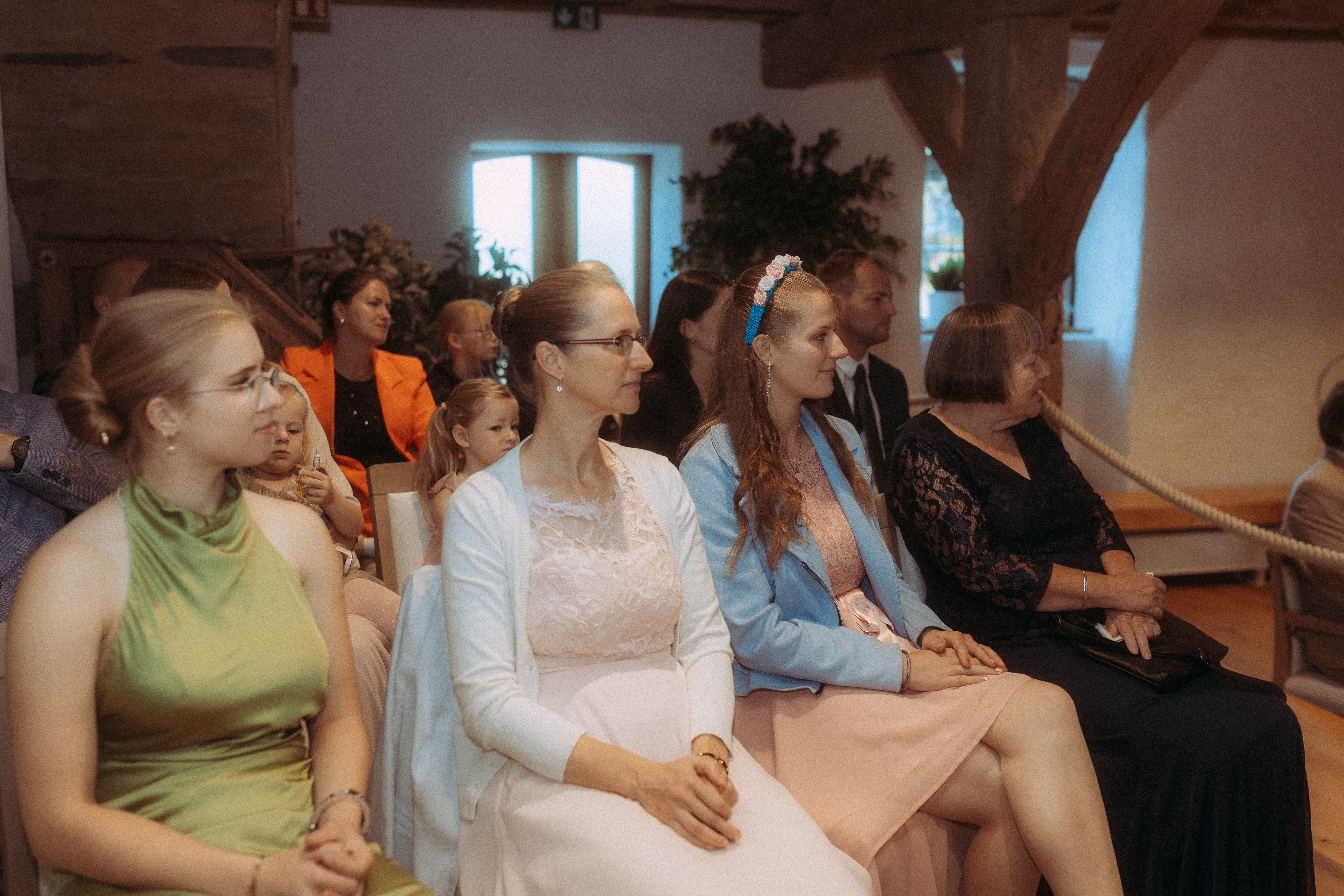 Gäste bei der standesamtlichen Hochzeit in Friedland (MV) sitzen auf Stühlen und schauen aufmerksam.