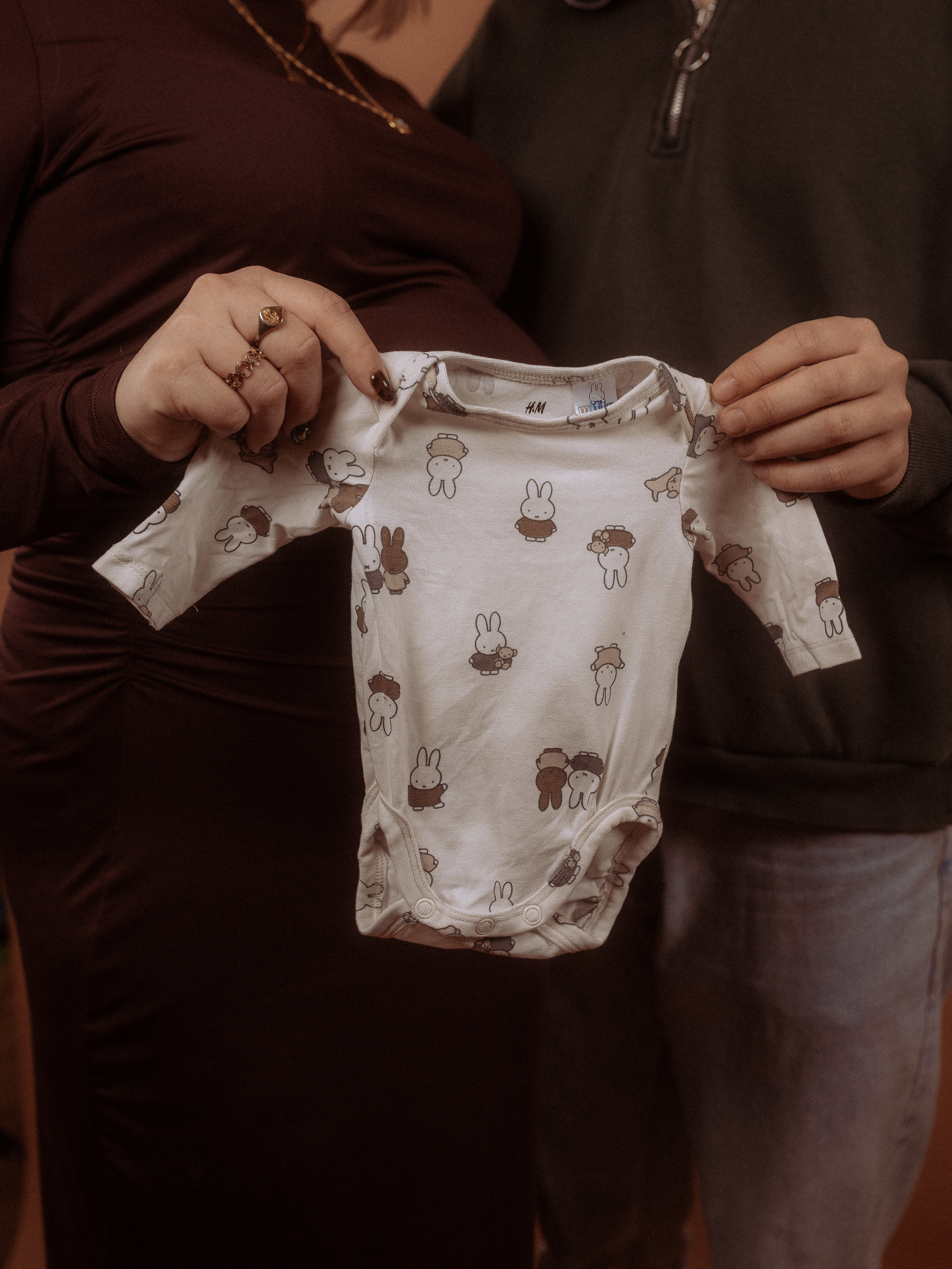 Babybauchshooting in Parchim: Paar hält Babybody mit Hasenmuster.