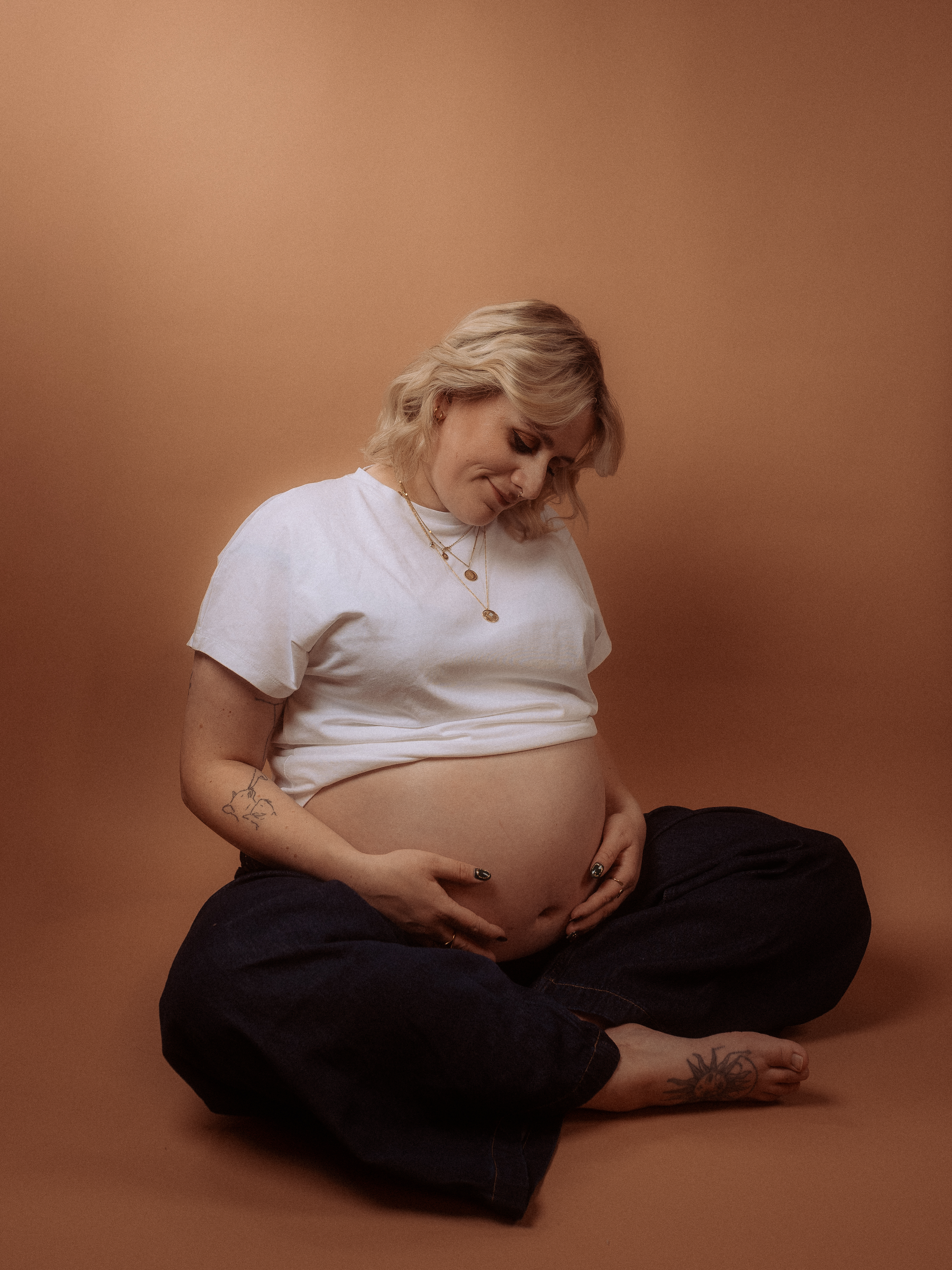 Schwangere Frau sitzt im Schneidersitz, Babybauchshooting in Parchim.