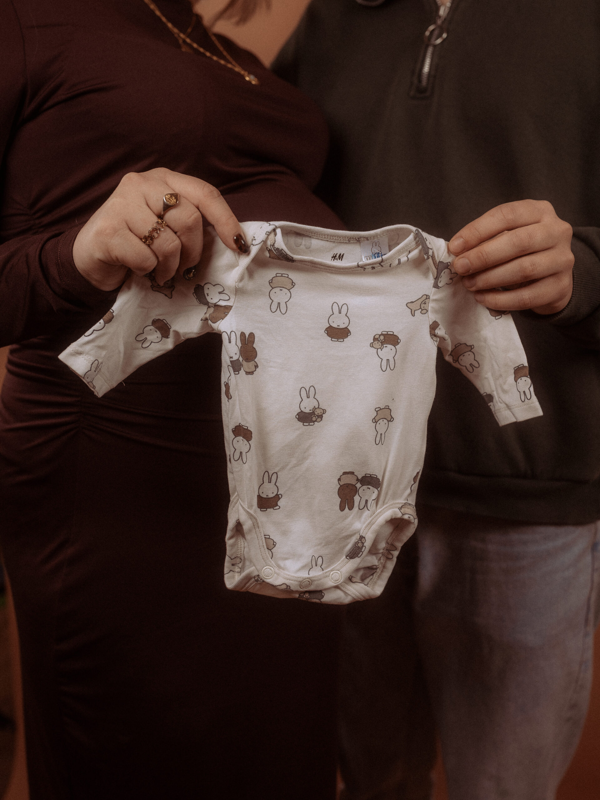 Babybauchshooting in Parchim: Paar hält Babybody mit Hasenmuster.