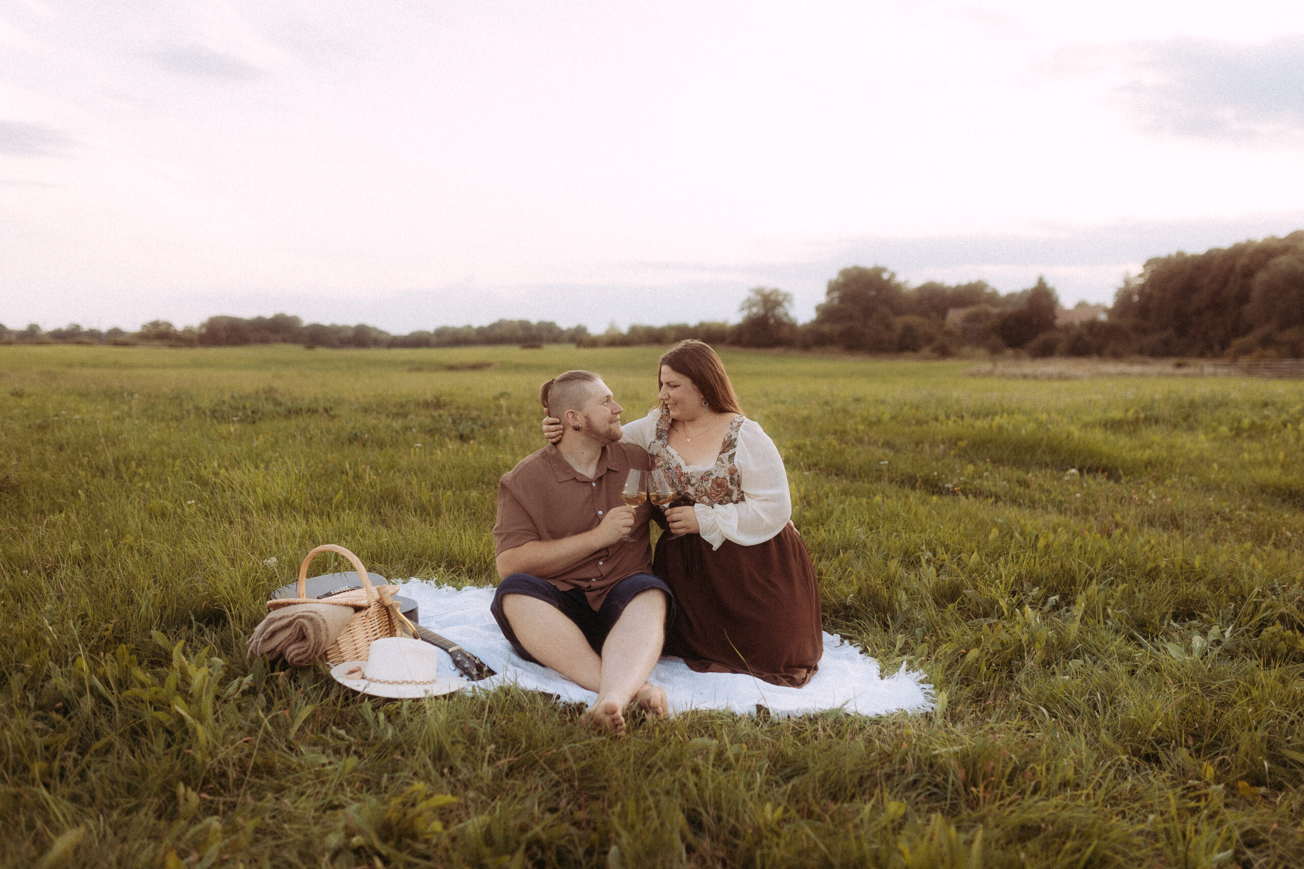 Romantisches Pärchenfoto in Röbel: Paar beim Picknick auf einer Wiese mit Wein.