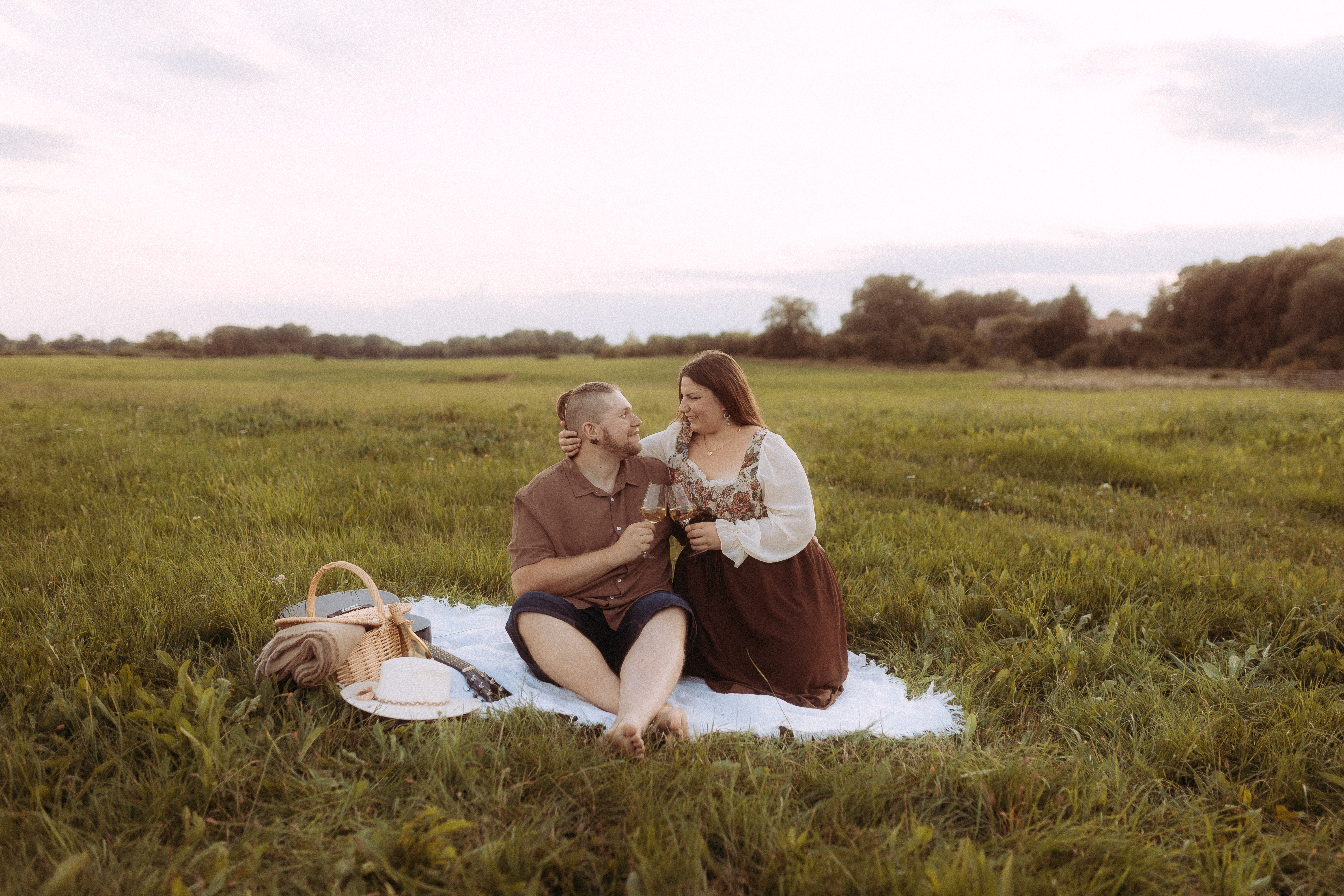 Romantisches Pärchenfoto in Röbel: Paar beim Picknick auf einer Wiese mit Wein.