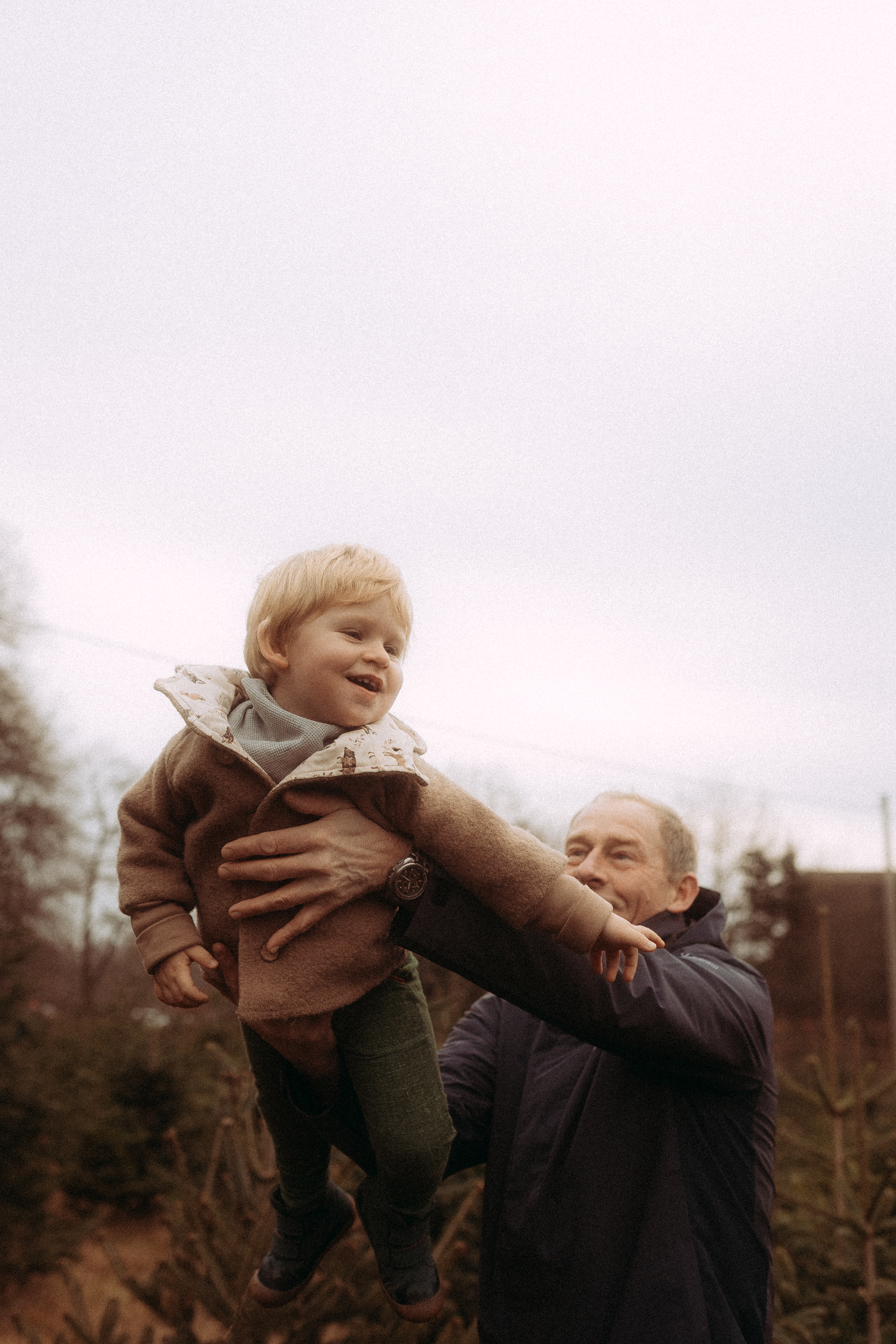 Lachender Vaterhebt sein Kind in Basthorst hoch. Familienfotoshooting.