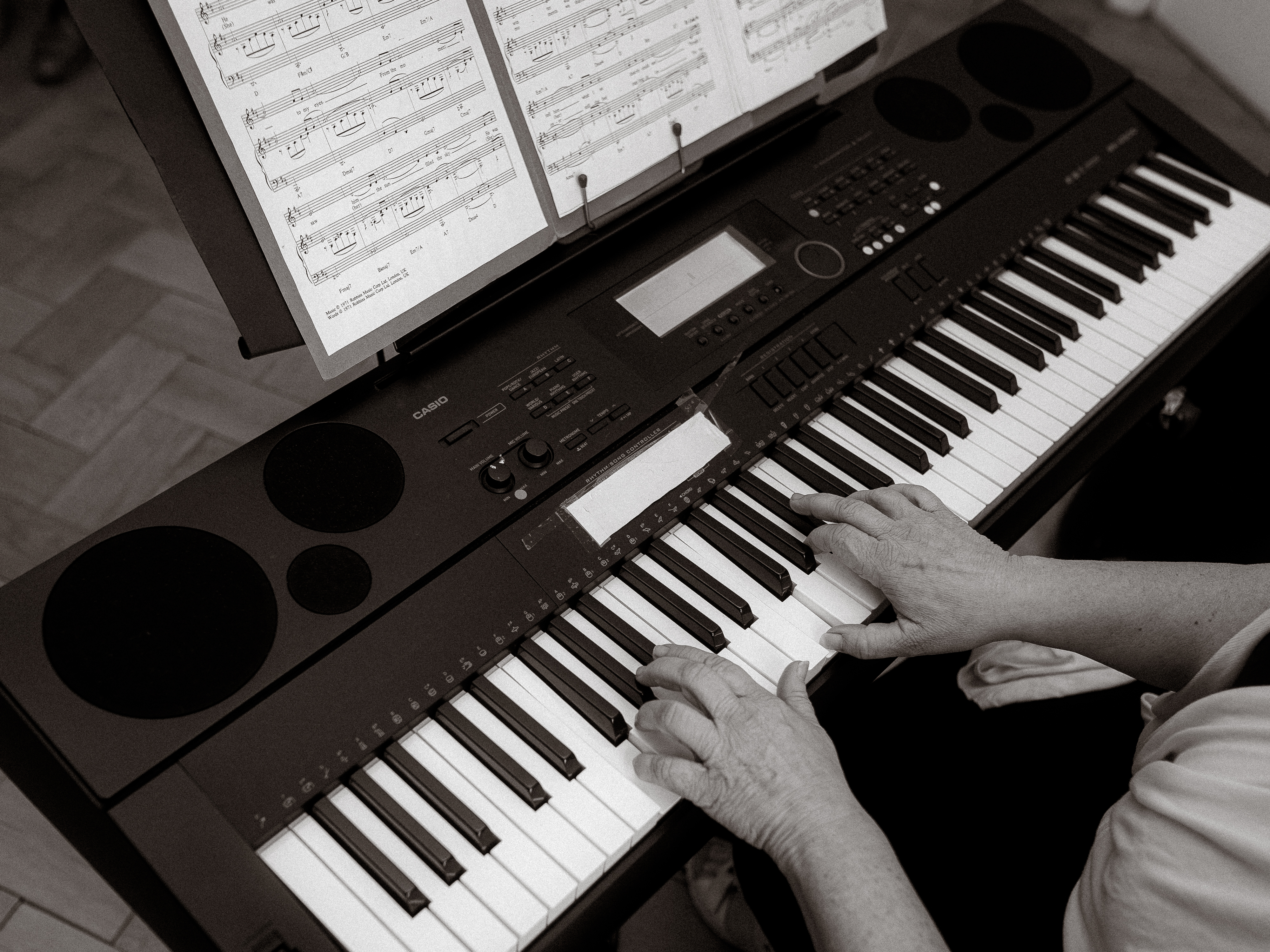 Hände spielen Klavier mit Noten. Casio Keyboard im Fokus.