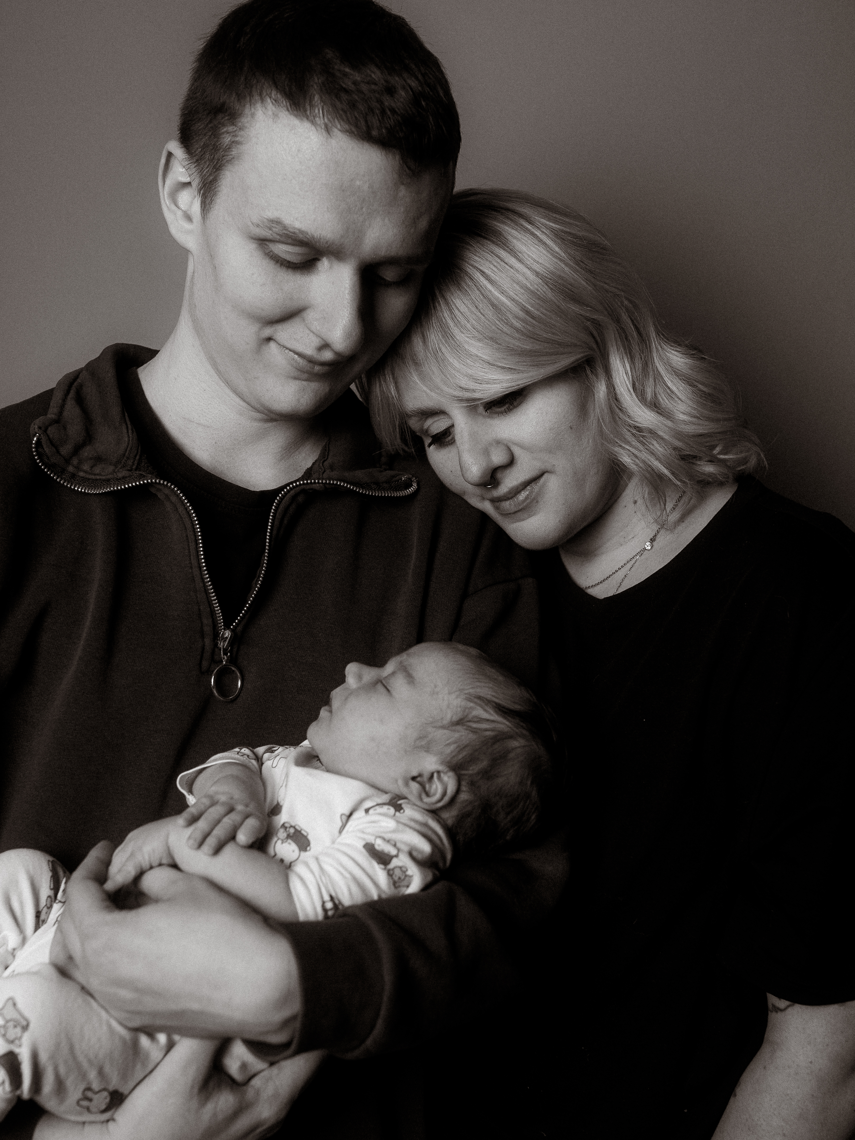 Junge Eltern halten ihr schlafendes Baby liebevoll im Arm. Familienglück und innige Verbundenheit