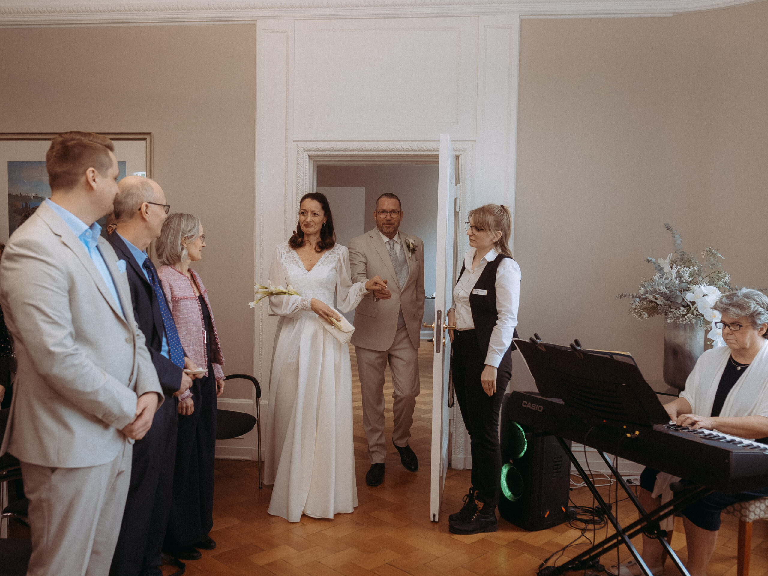 Brautpaar betritt Raum zur Trauung, Gäste und Pianistin anwesend