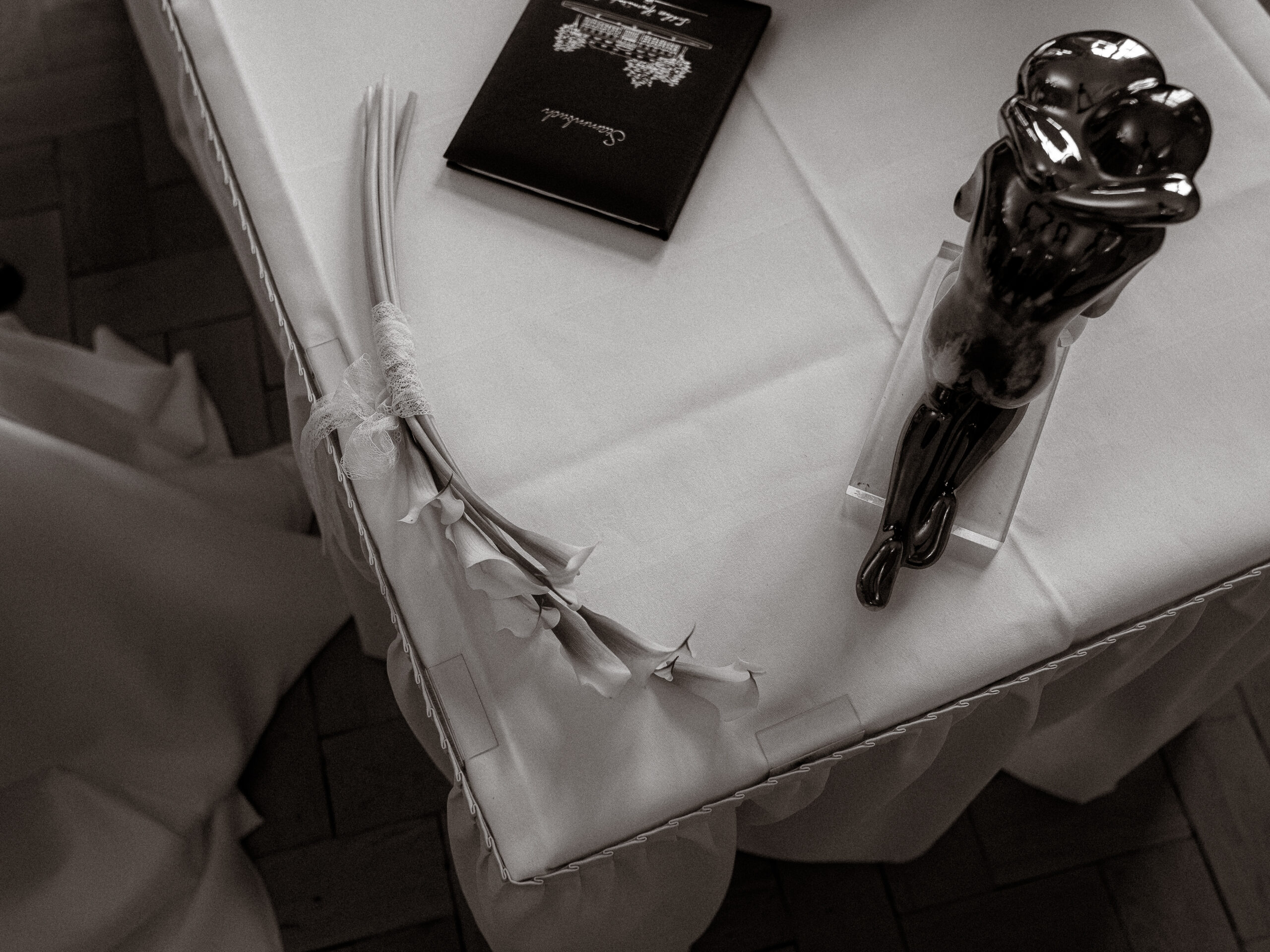 Ehebuch, Blumenstrauß und Skulptur eines Paares auf weißer Tischdecke. Heiratsantrag oder Hochzeit.