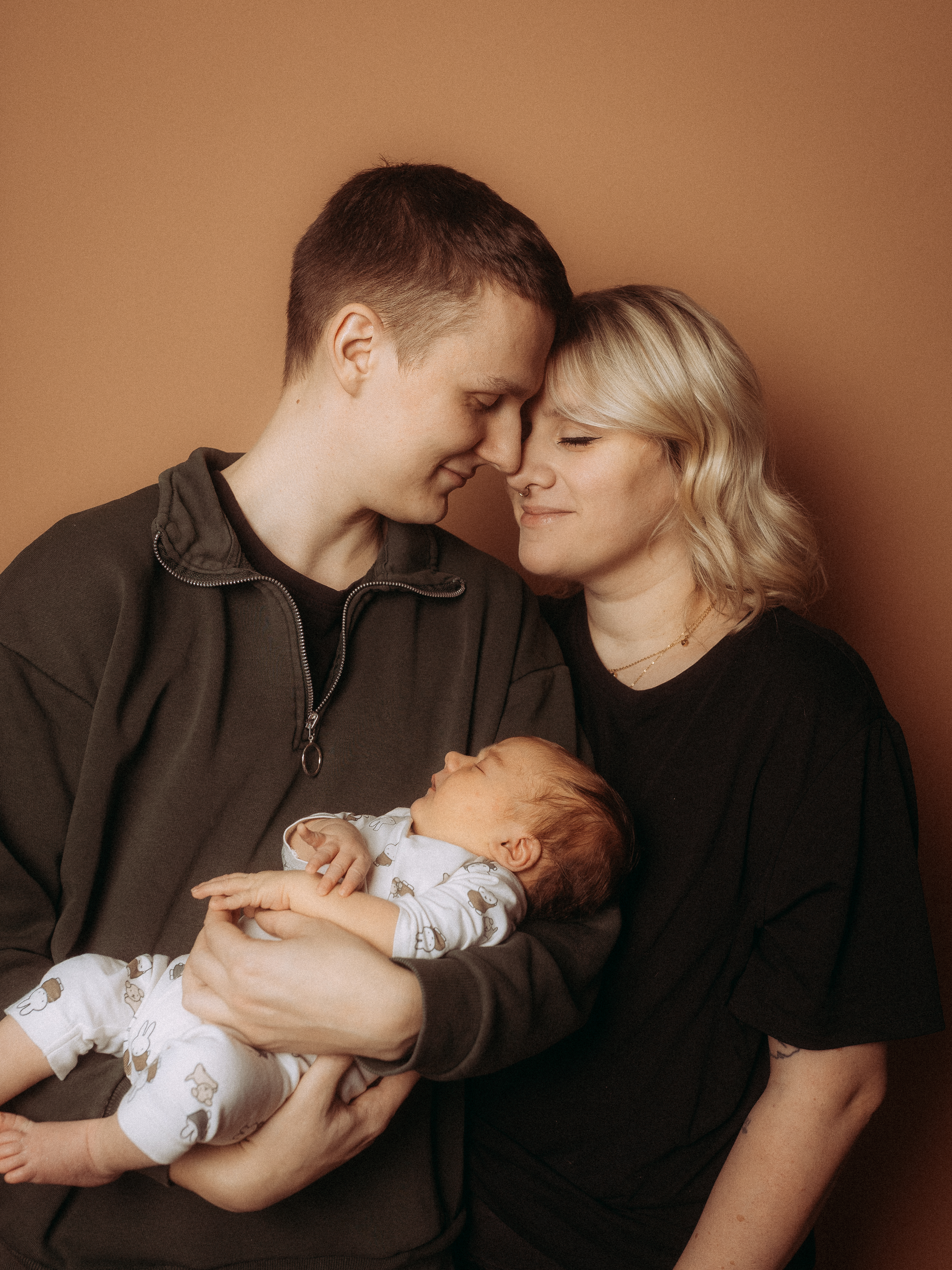 Glückliche Eltern mit Neugeborenen. Liebevolle Familie, Vater hält Baby im Arm, Mutter lächelt.