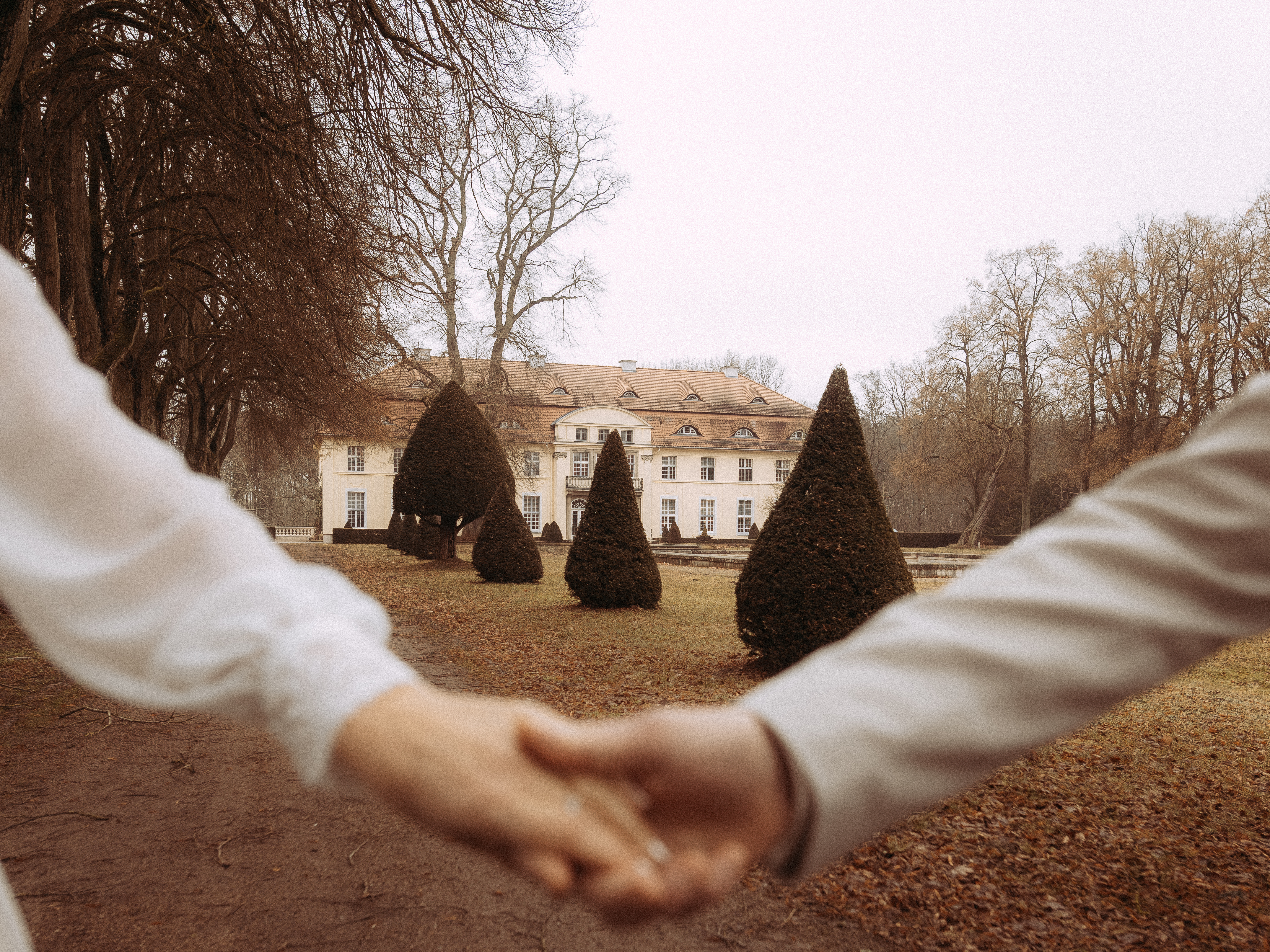 Händchenhaltendes Paar vor Schloss im Herbst. Romantische Szene.
