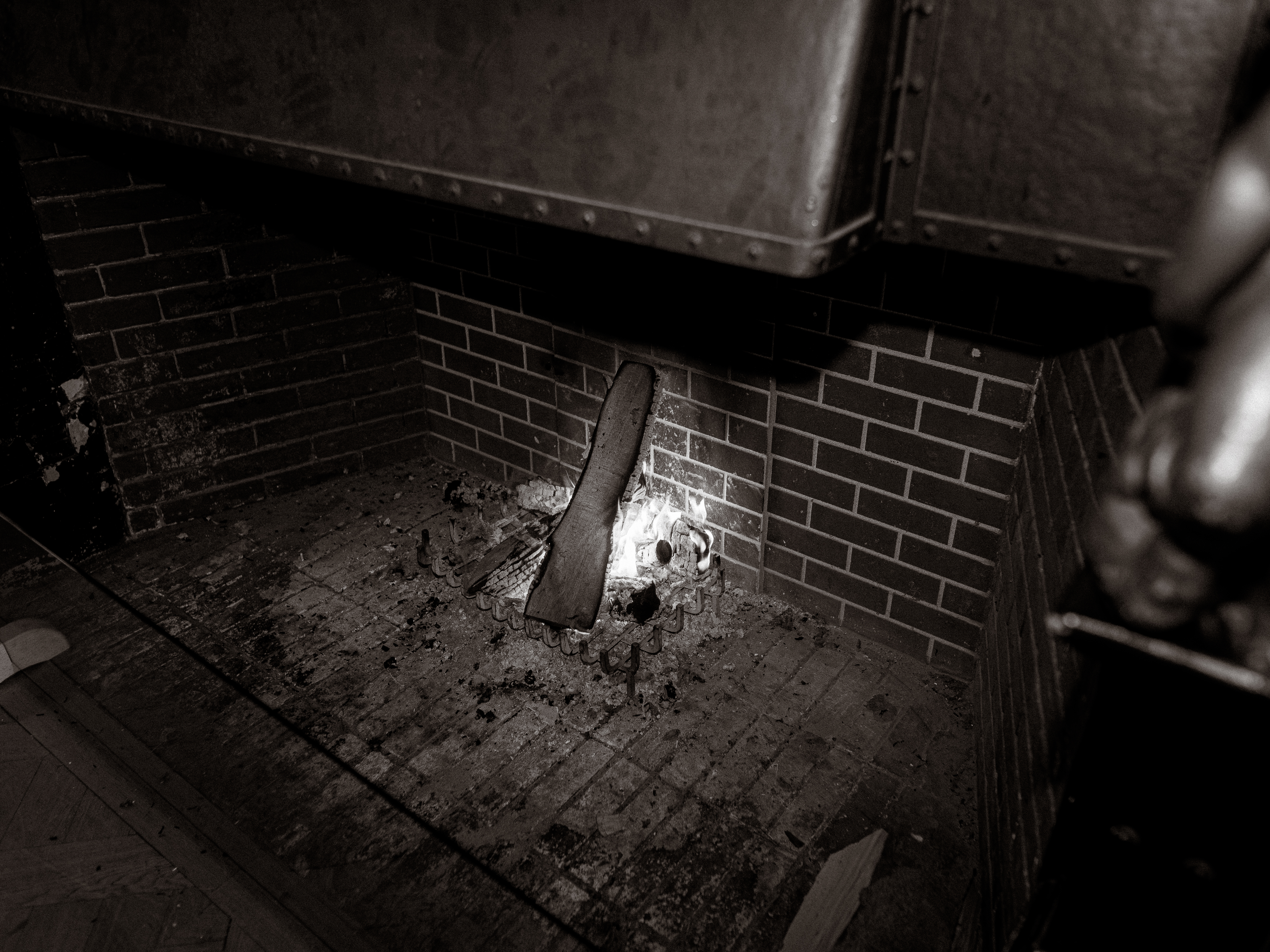 Kaminfeuer mit Holzscheit und Asche in einem Backsteinkamin.