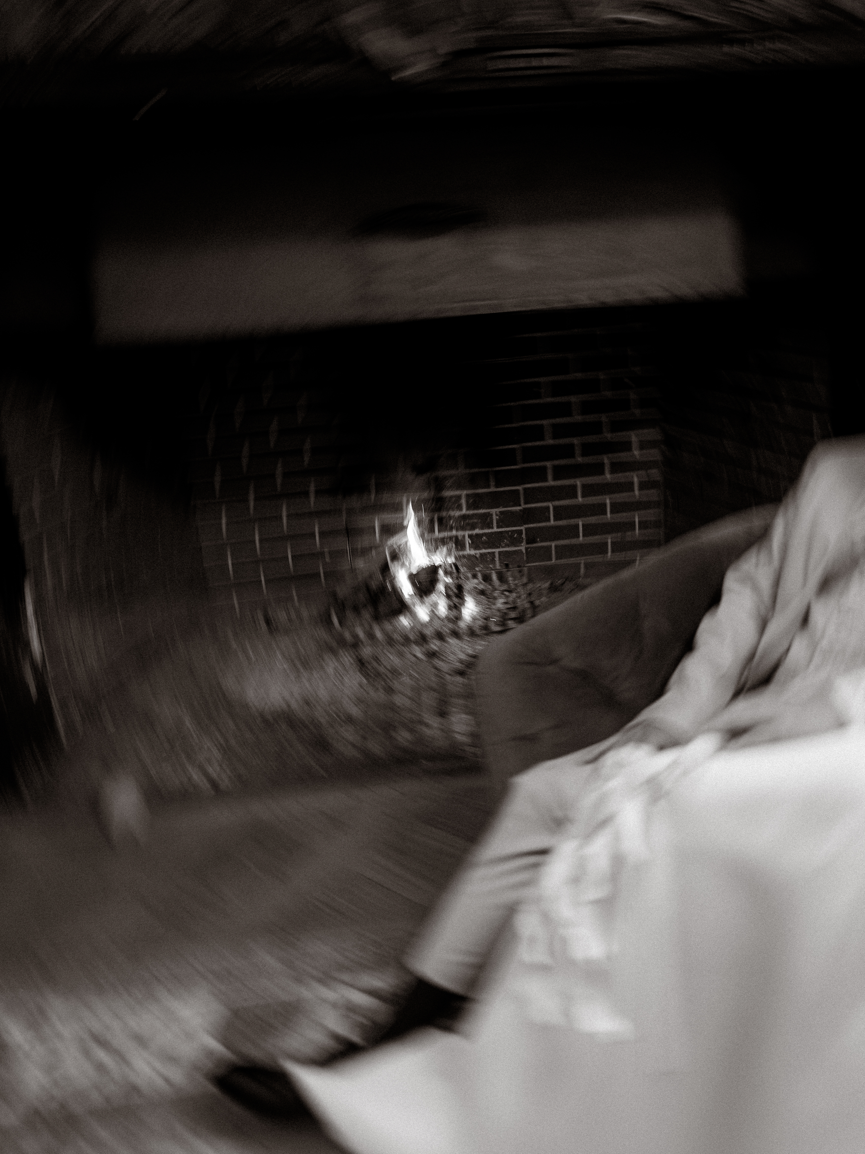 Verschwommenes Foto eines Kamins mit einem Feuer und einer Person auf einem Sofa