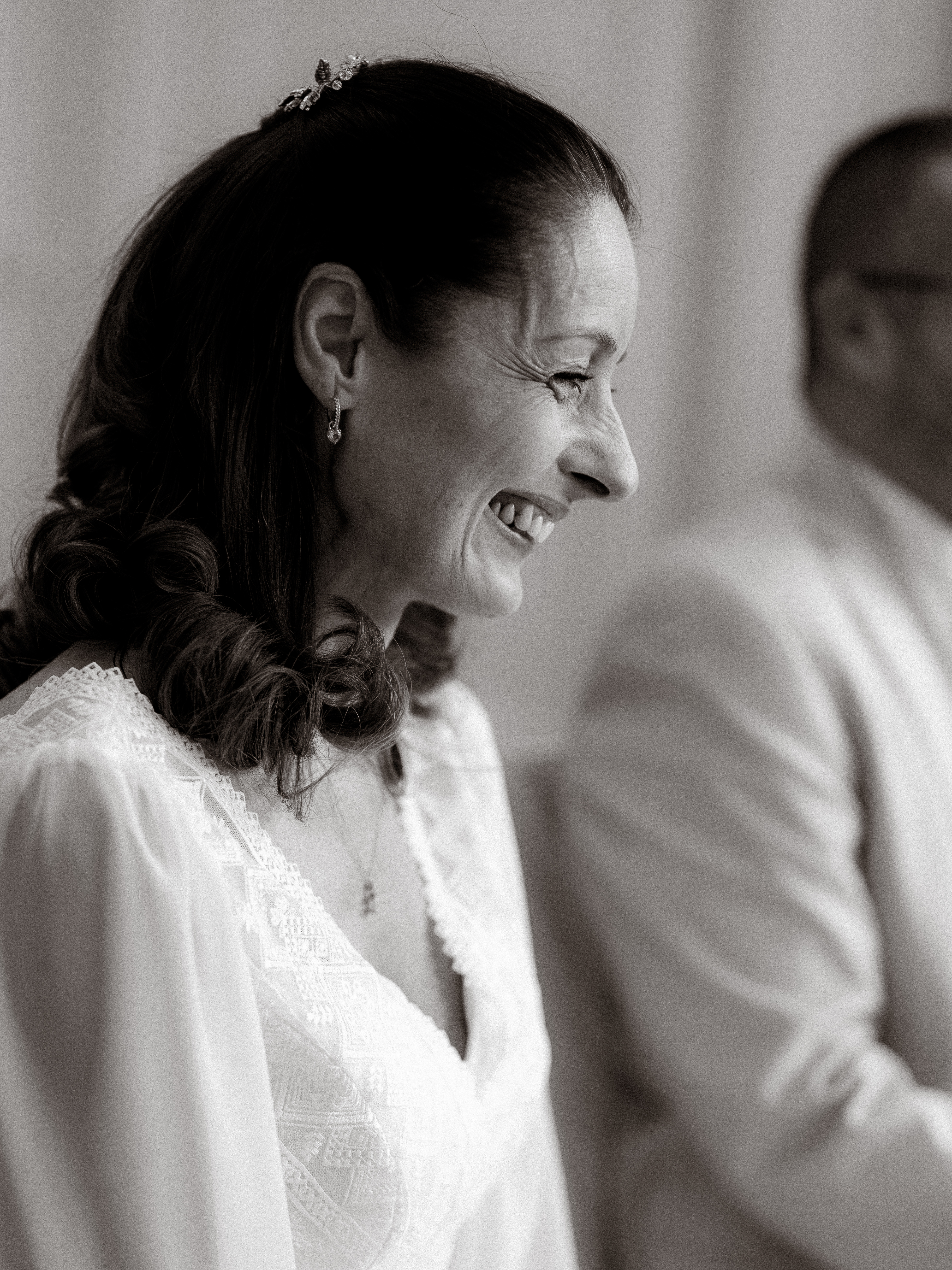 Lächelnde Frau im weißen Kleid mit Spitze und Schmuck im Haar