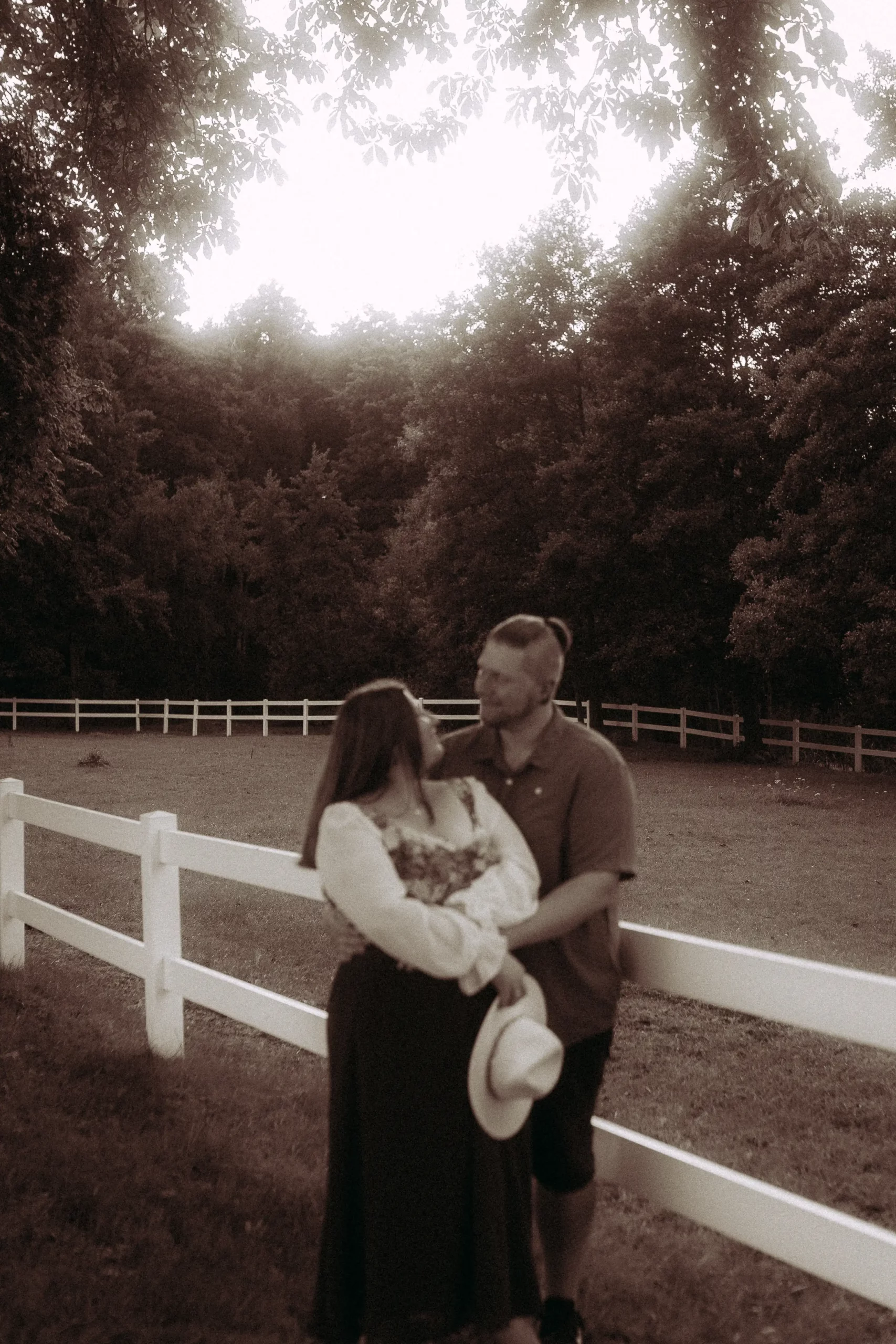 Couple embracing by a white fence outdoors
