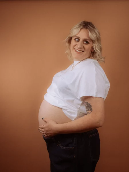 Schwangere Frau lächelt und hält ihren Bauch