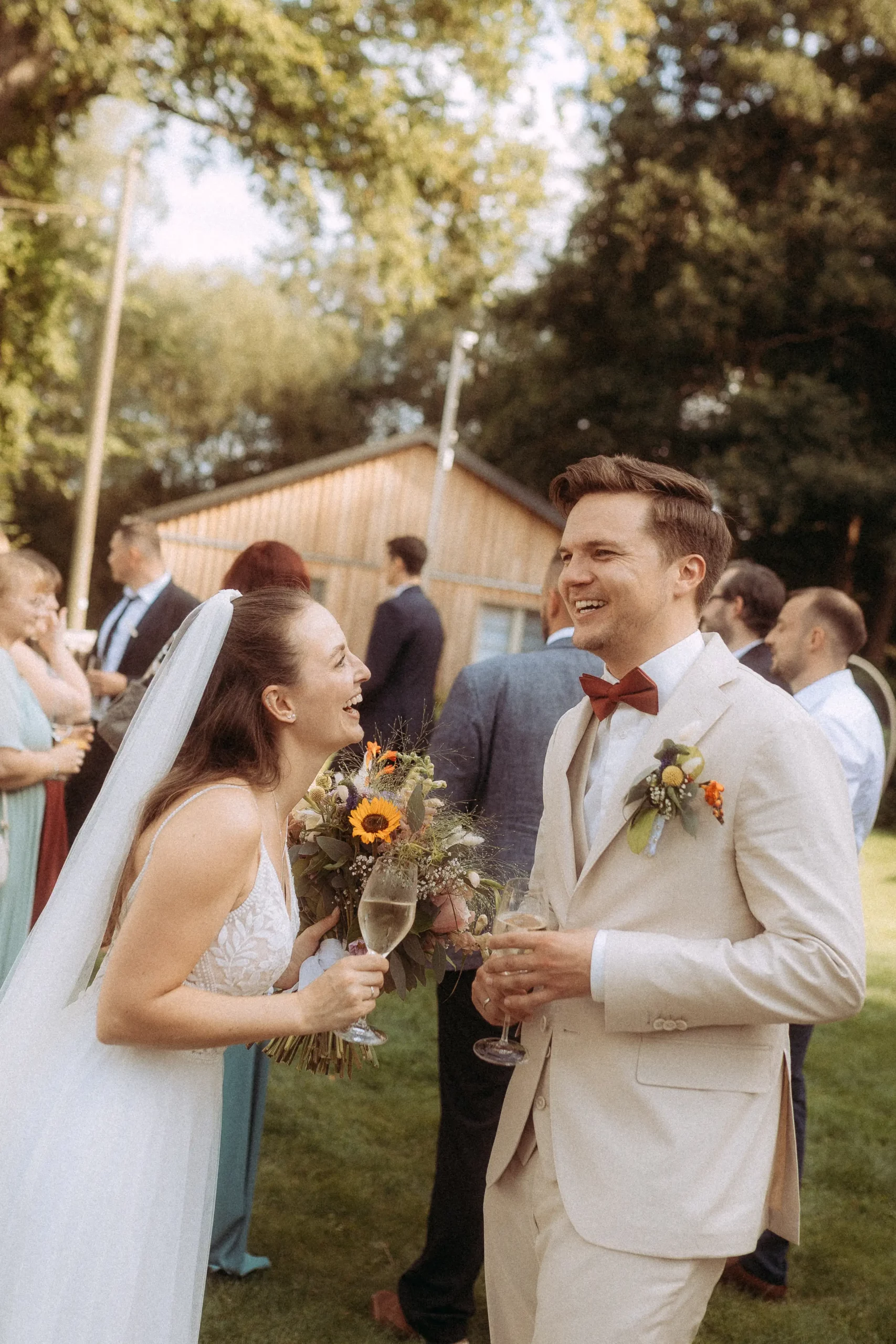 Brautpaar lacht mit Sektgläsern auf Hochzeit