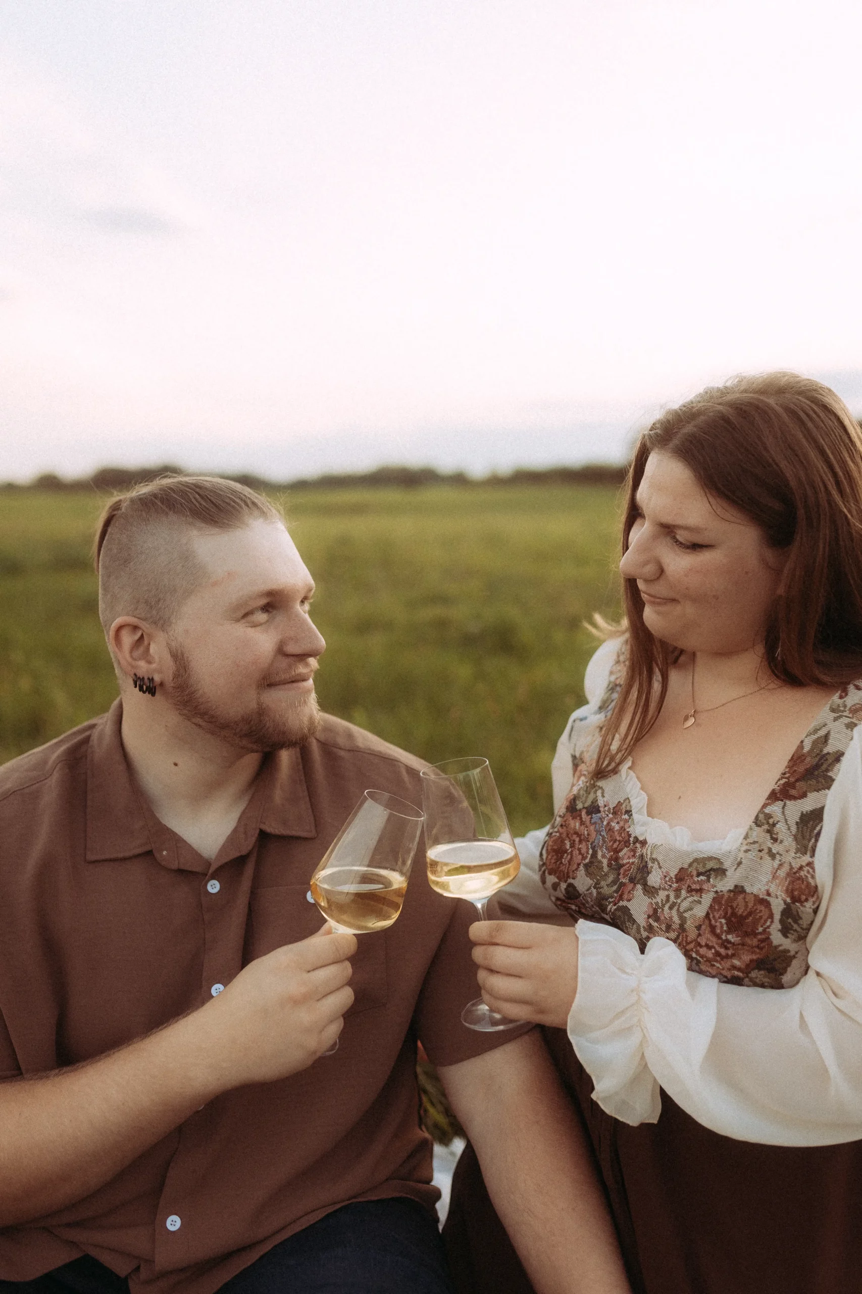Couple toasting wine glasses at picnic