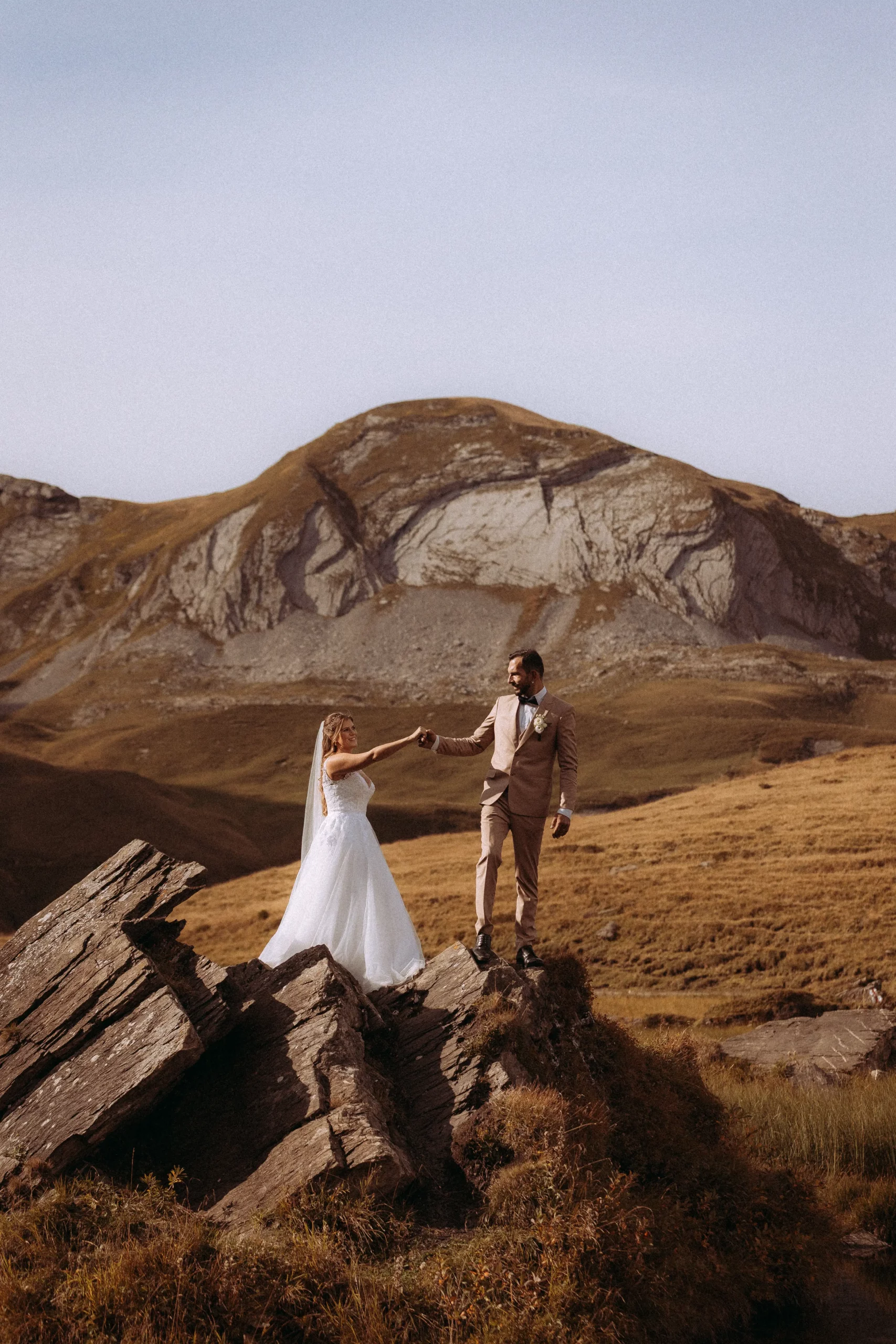 Hochzeitspaar auf Felsen vor Bergkulisse