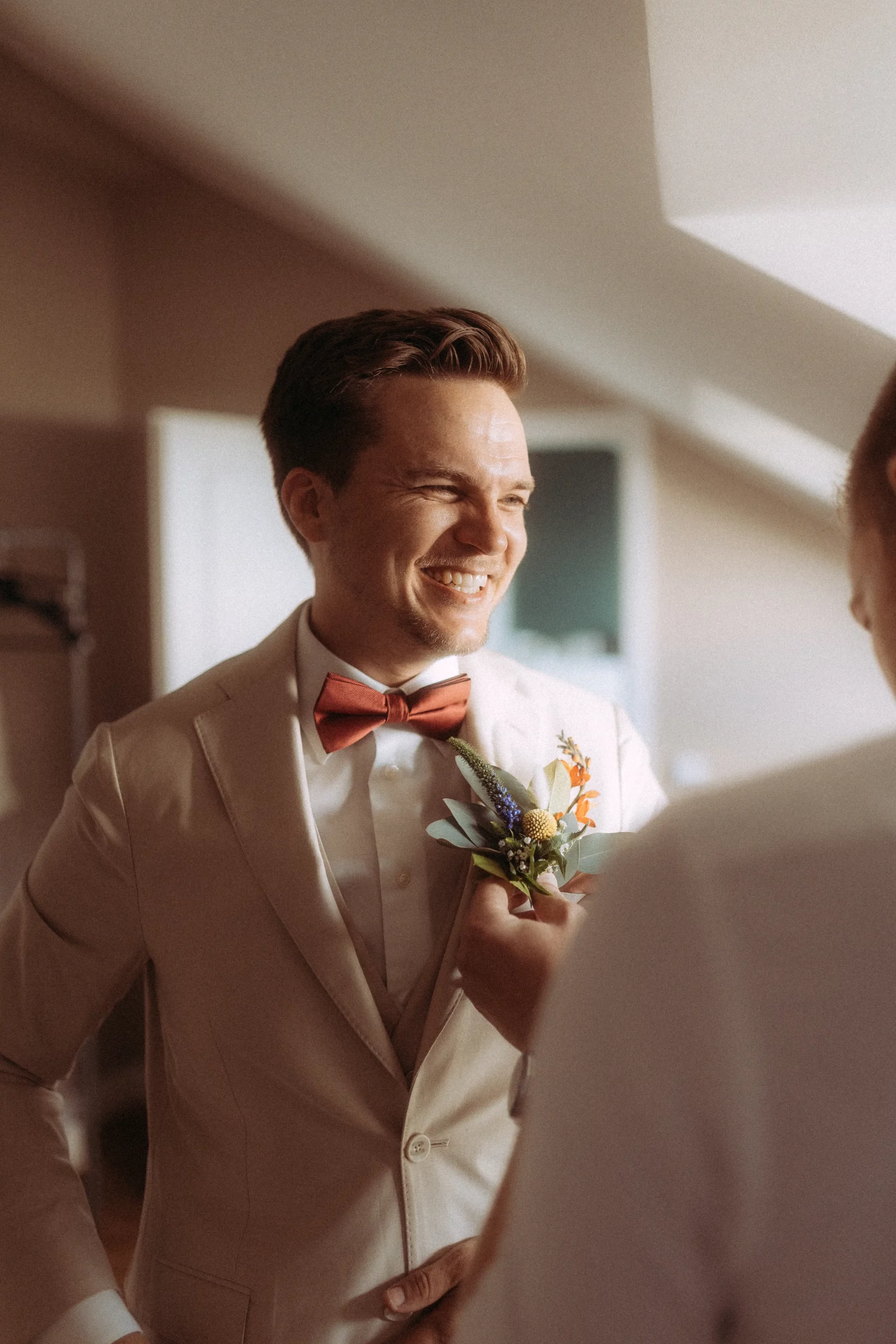 Bräutigam lächelt mit Blume am Revers