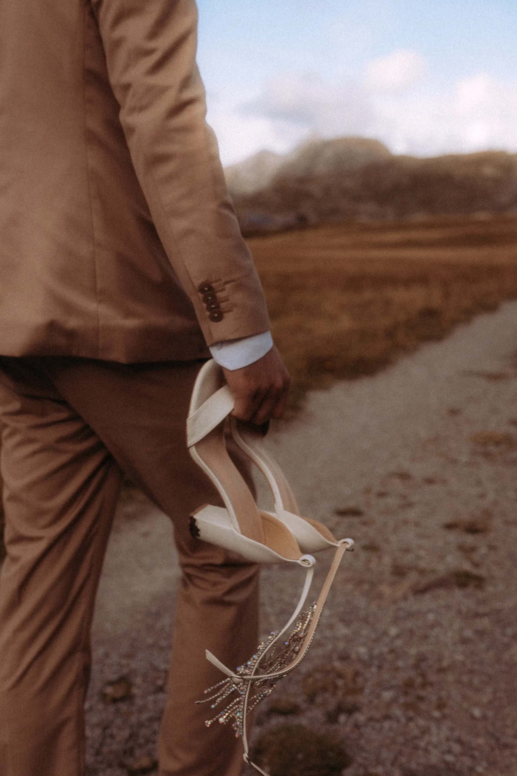 Mann trägt Brautschuhe über Feldweg